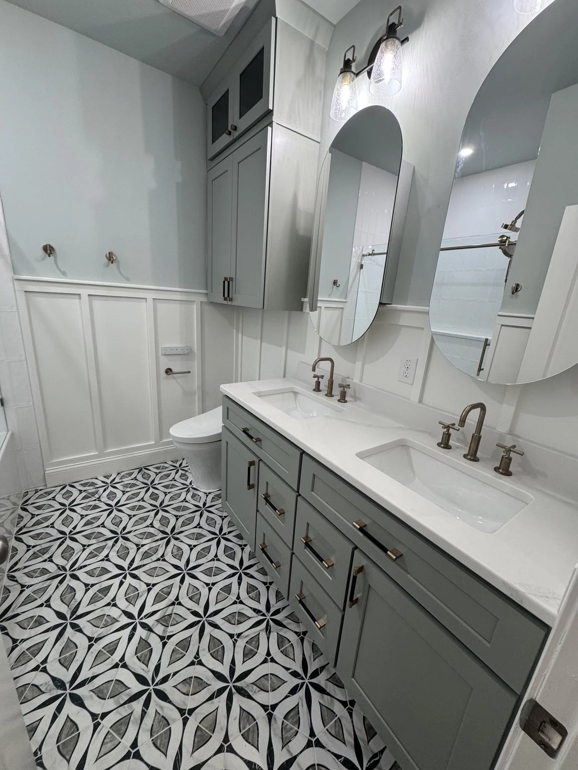 Soft gray cabinets, warm metal finishes, and a playful floor pattern bring a little extra charm to the daily routine.