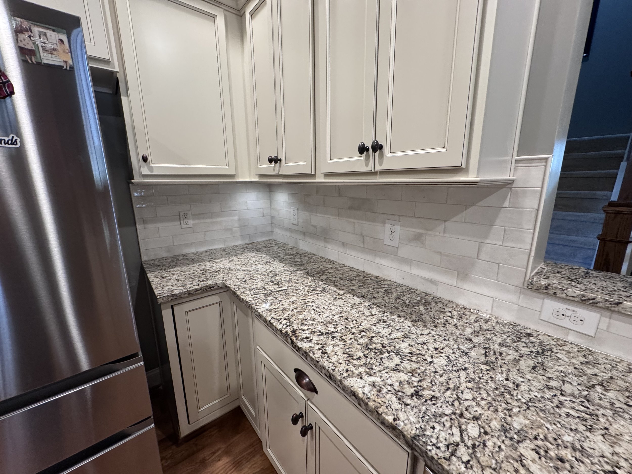 Soft lighting brings out the texture of the backsplash, adding a warm glow to this everyday kitchen corner.