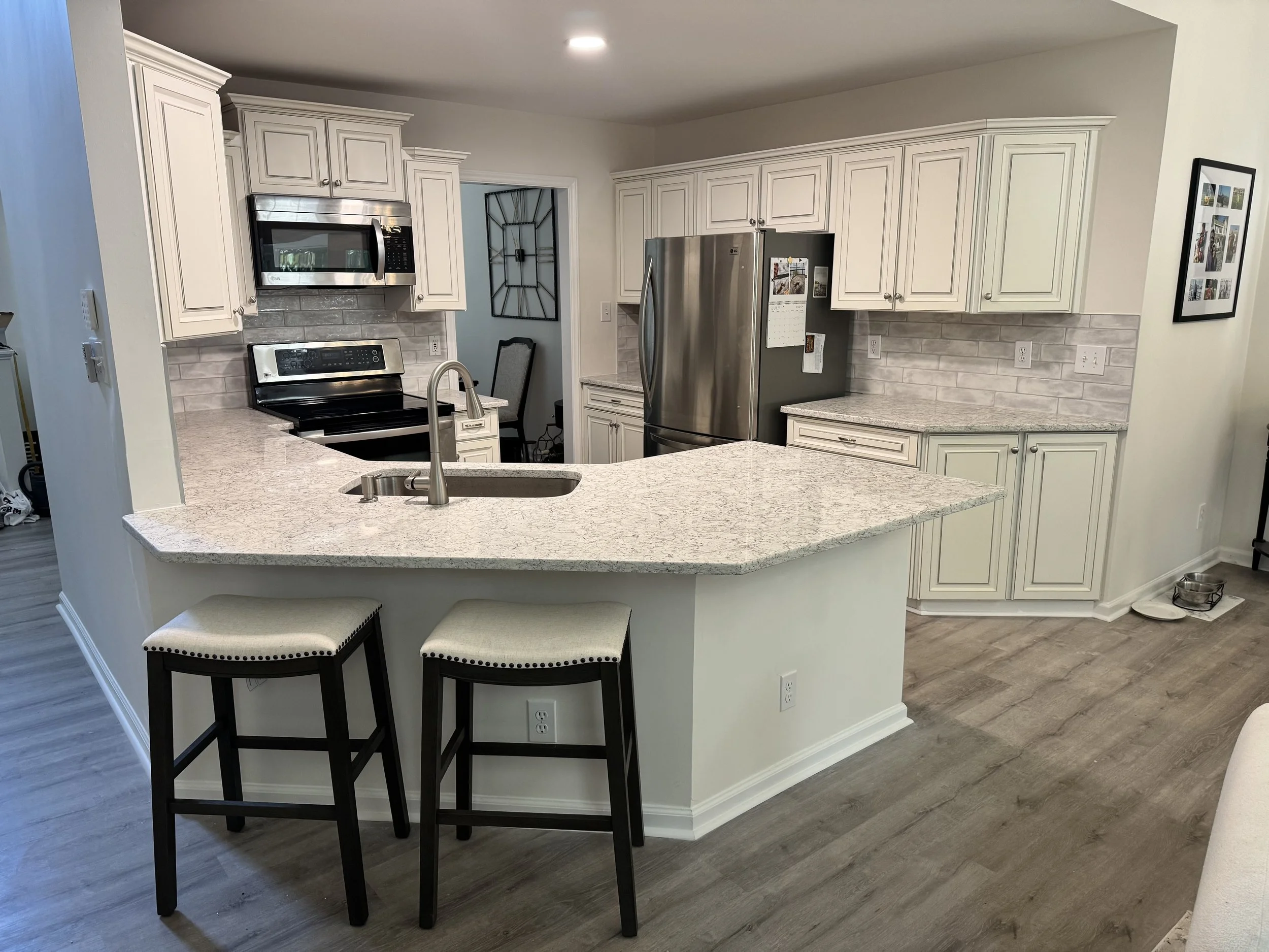 Light countertops and a fresh backsplash give this familiar kitchen a brighter feel, with a spot at the peninsula to pull up a chair.