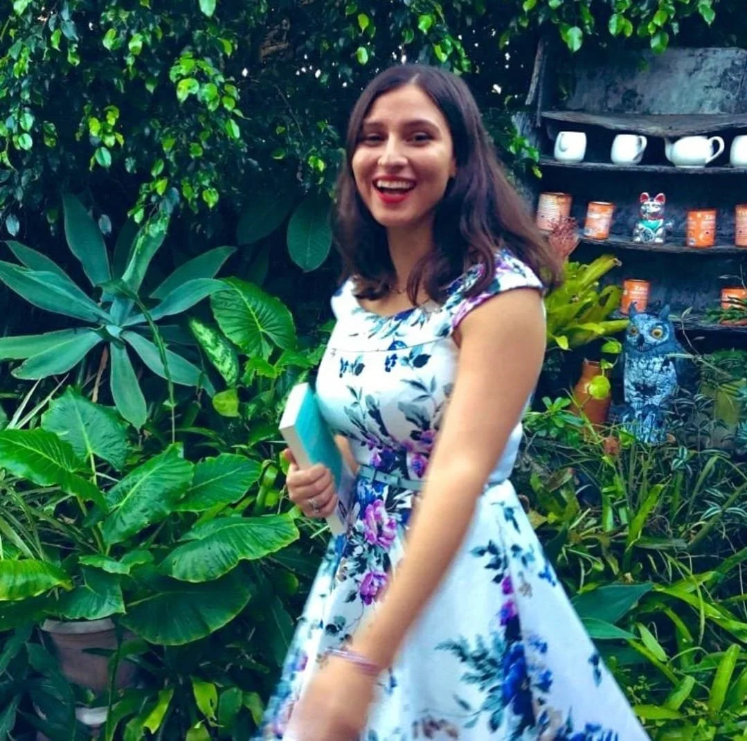 A colour photo of Steph Bowe, who is smiling and holding her YA novel 'Night Swimming'.
