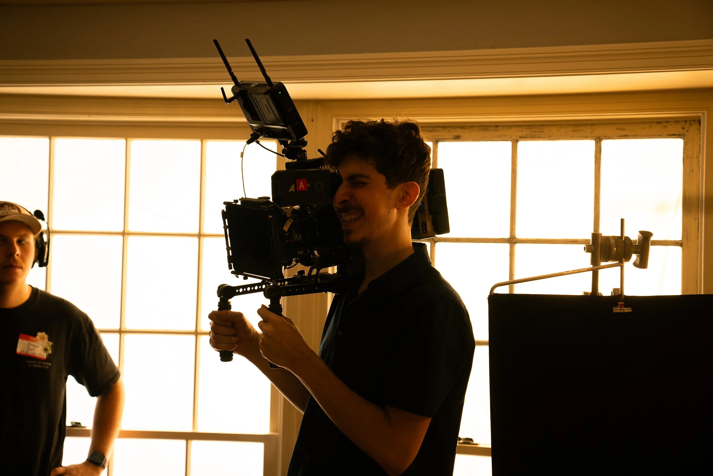 Cinematographer operating a professional video camera on a shoulder rig indoors