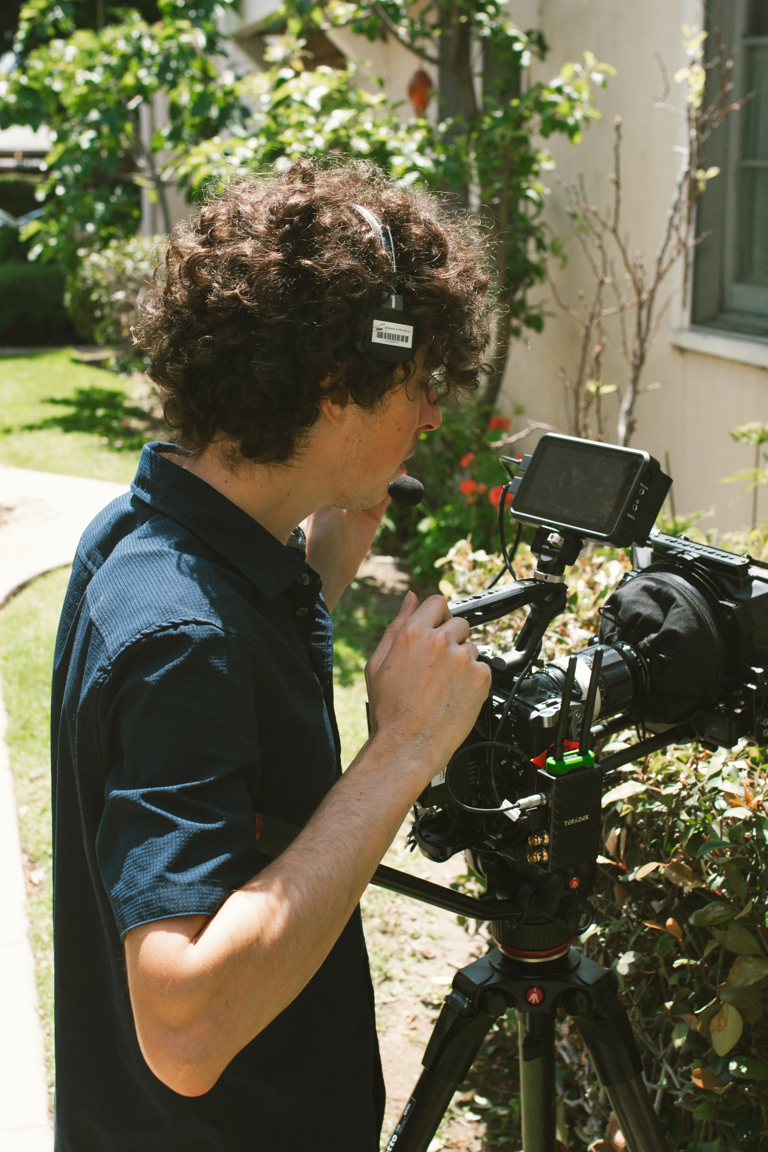 Filmmaker operating a professional cinema camera outdoors in a sunlit garden