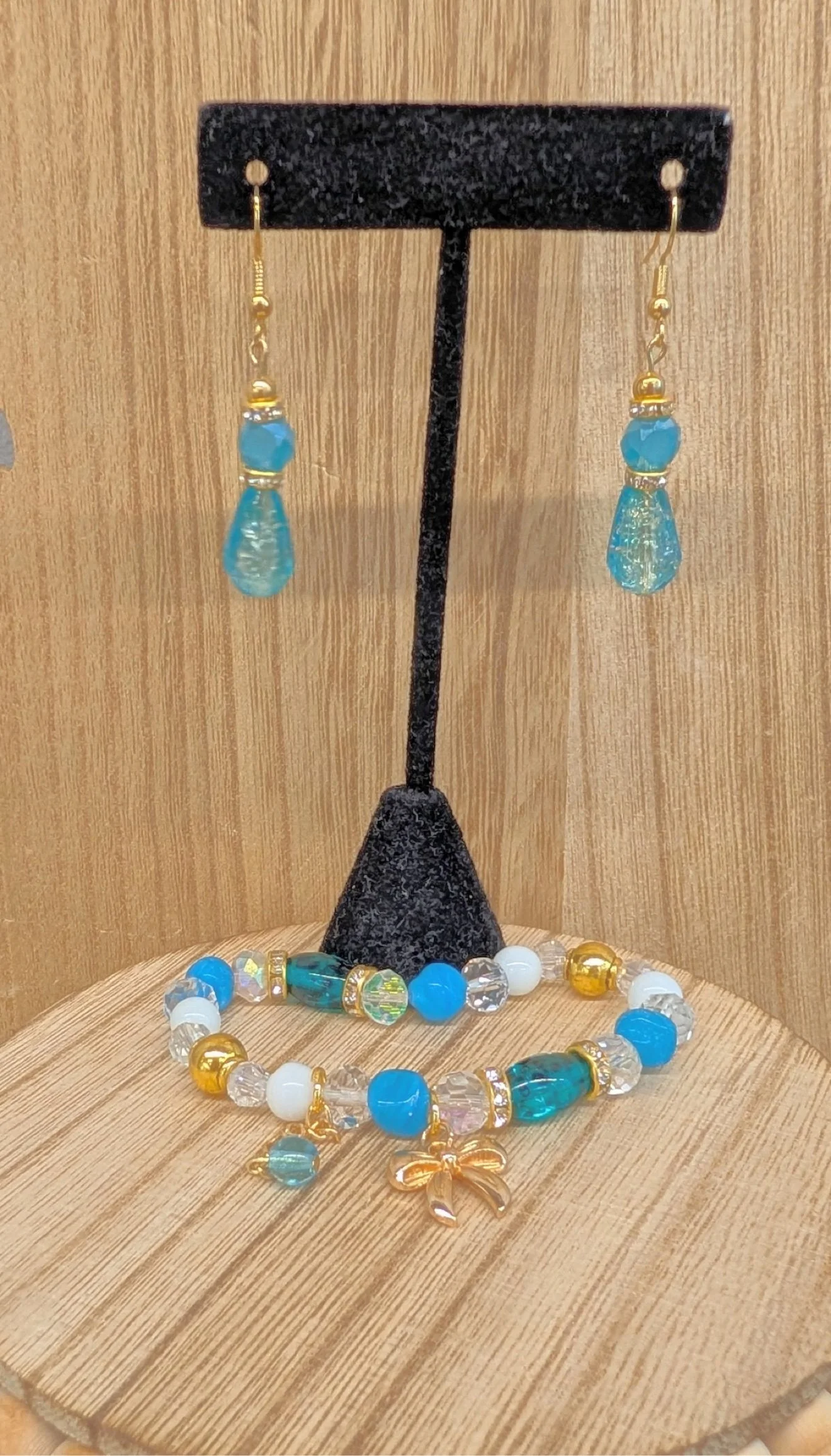Blue teardrop earrings with matching charm bracelet on a stand