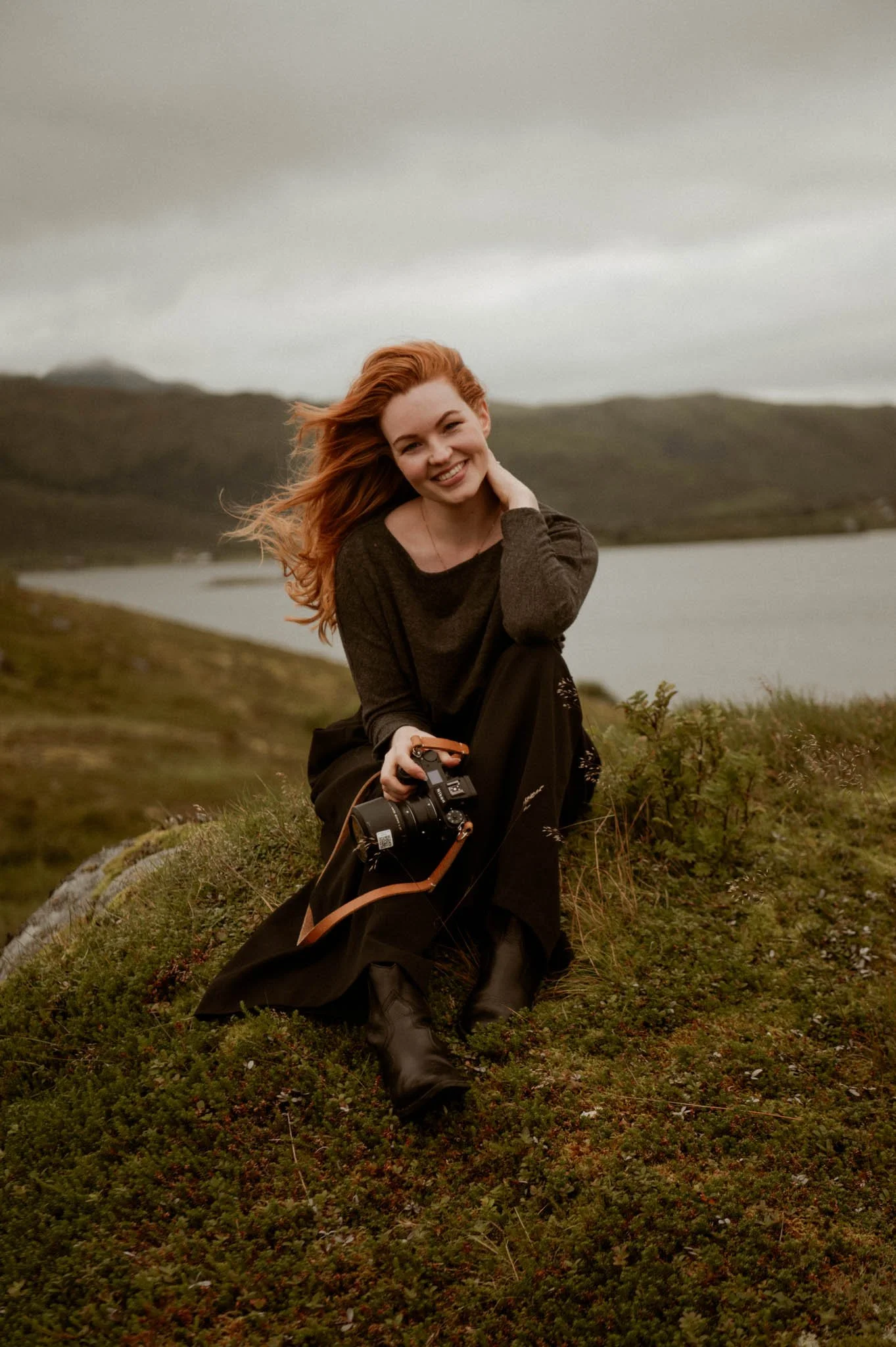 A travel photographer sitting in the grass on a hill in Lofoten, Northern Norway
