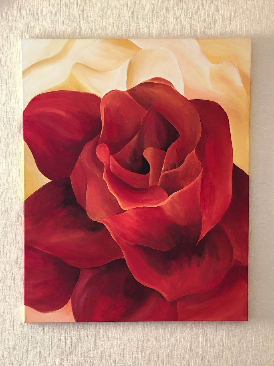 An acrylic painting of a red rose with petals in various shades of red, against a soft, warm background.