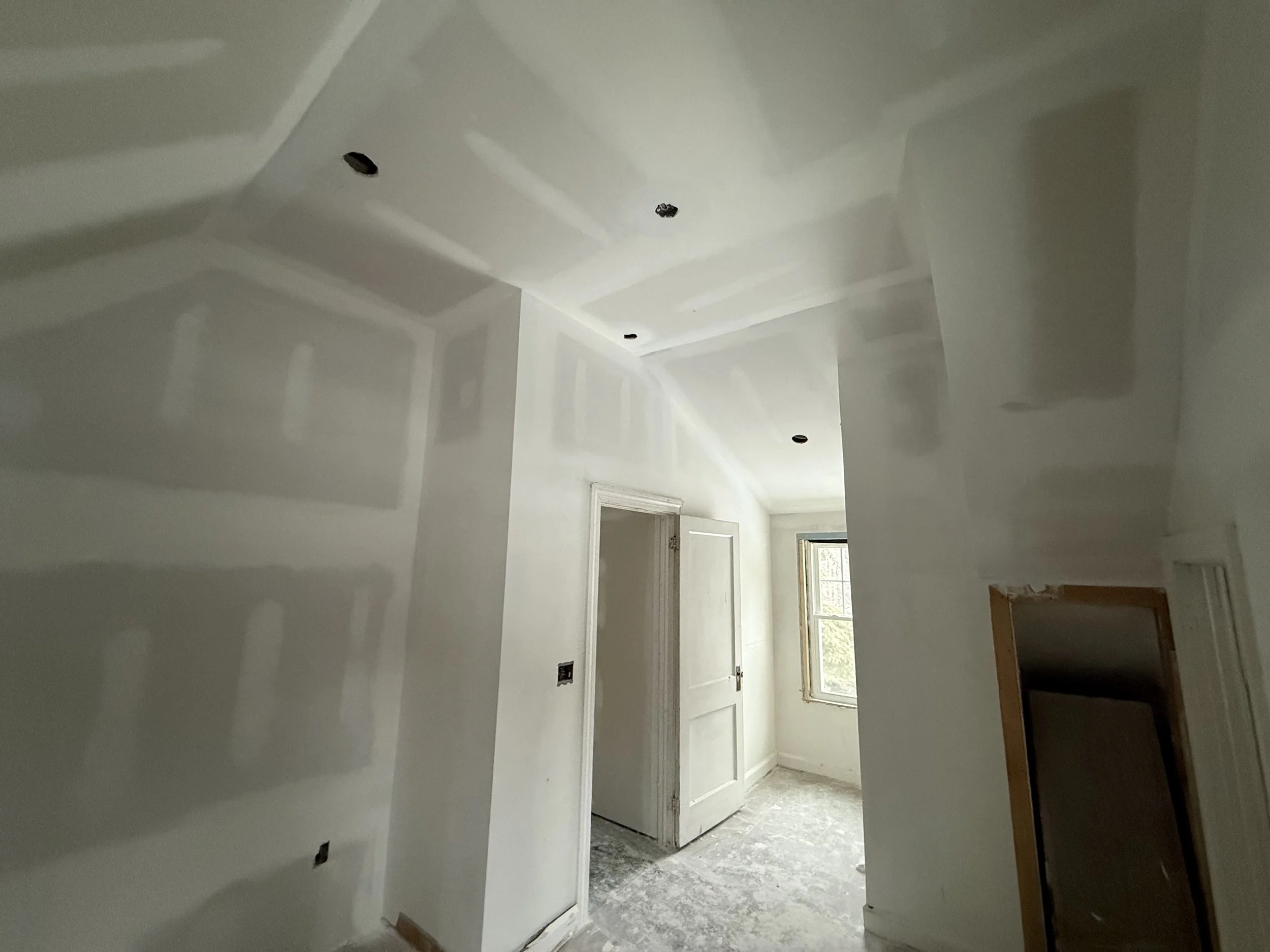 Empty room with unfinished drywall and missing light fixtures.