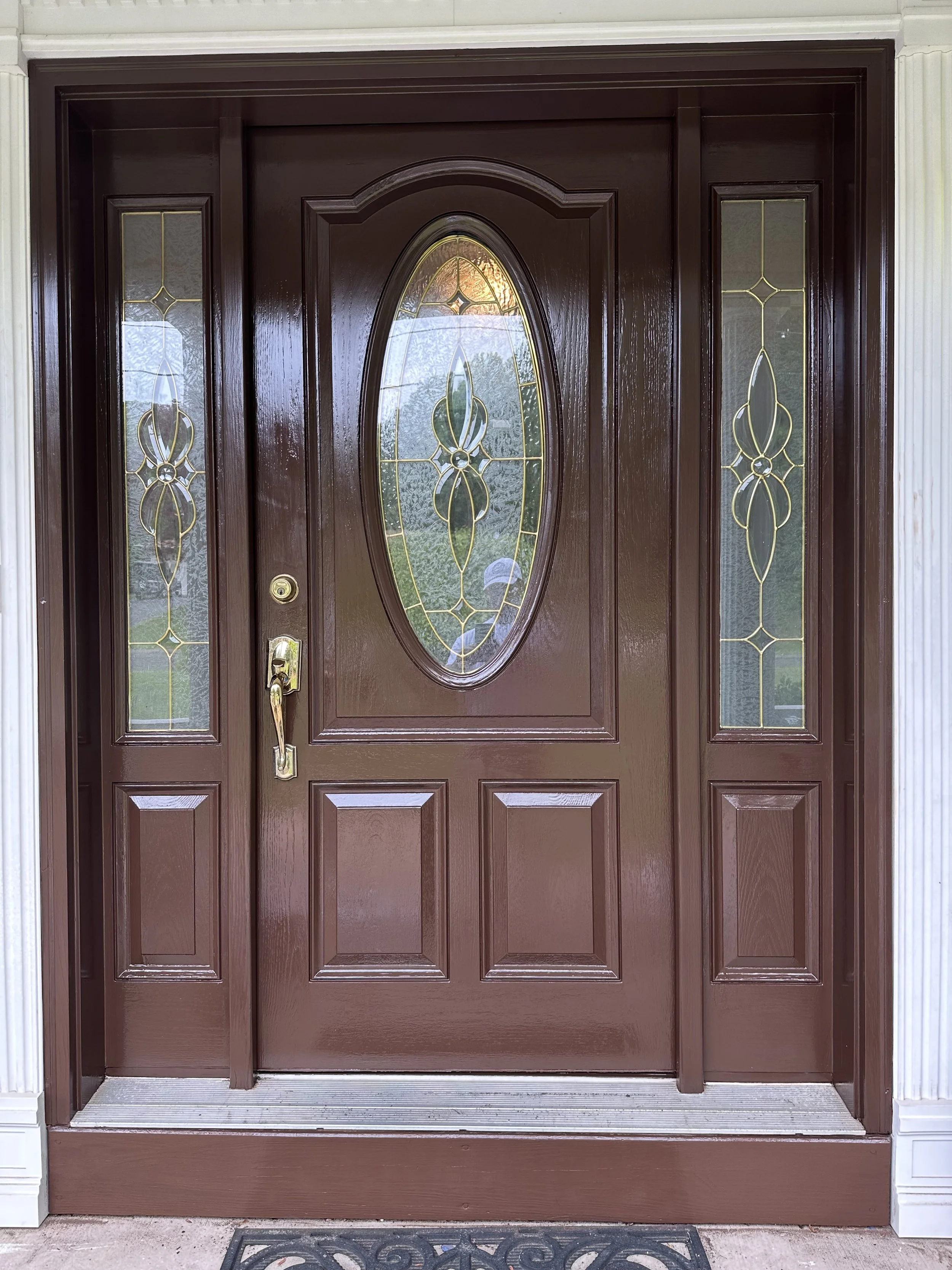 A wooden front door with decorative glass panels and brass hardware.