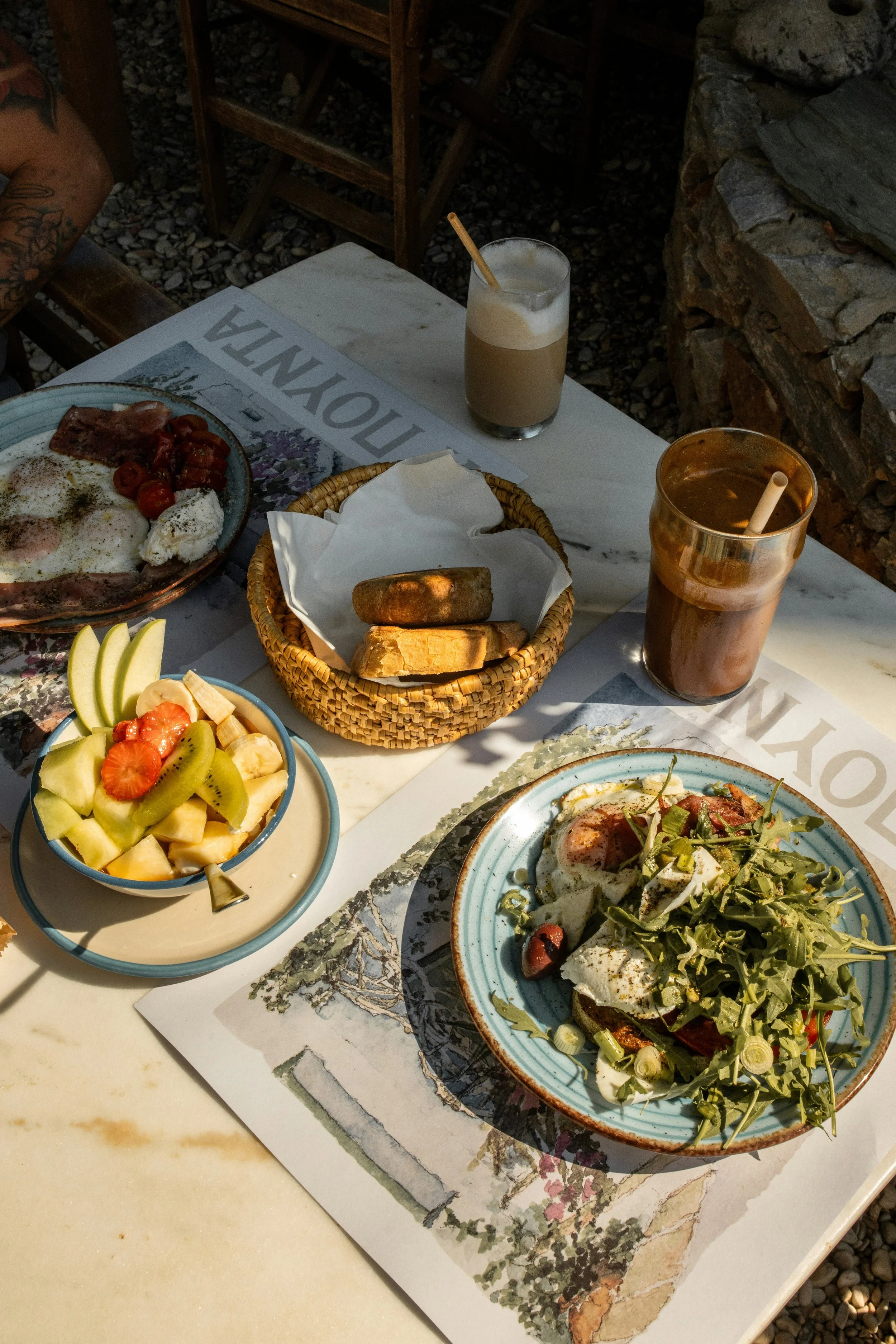 A table set for breakfast with fruit, eggs and bacon and drinks.