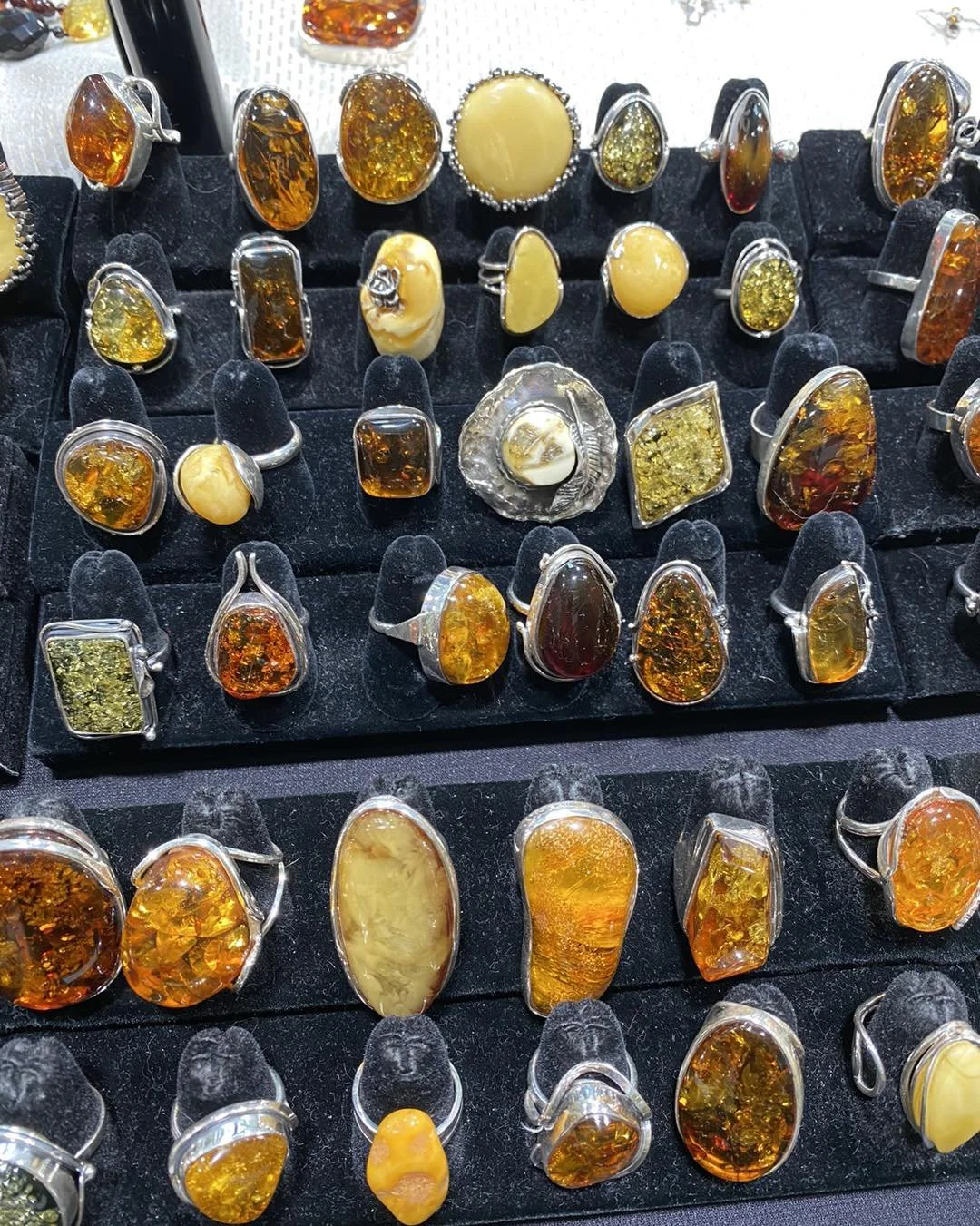 A display of various amber gemstone rings on a black velvet stand.
