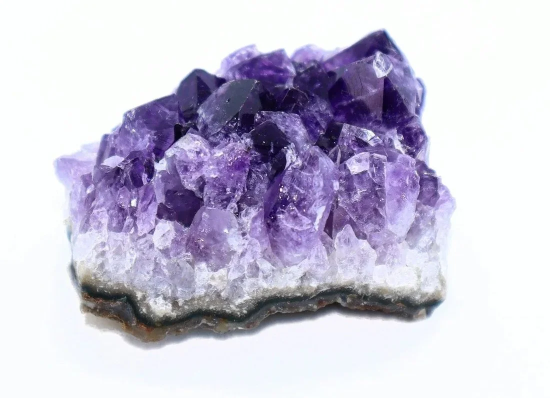 A cluster of purple amethyst crystals on a white background.