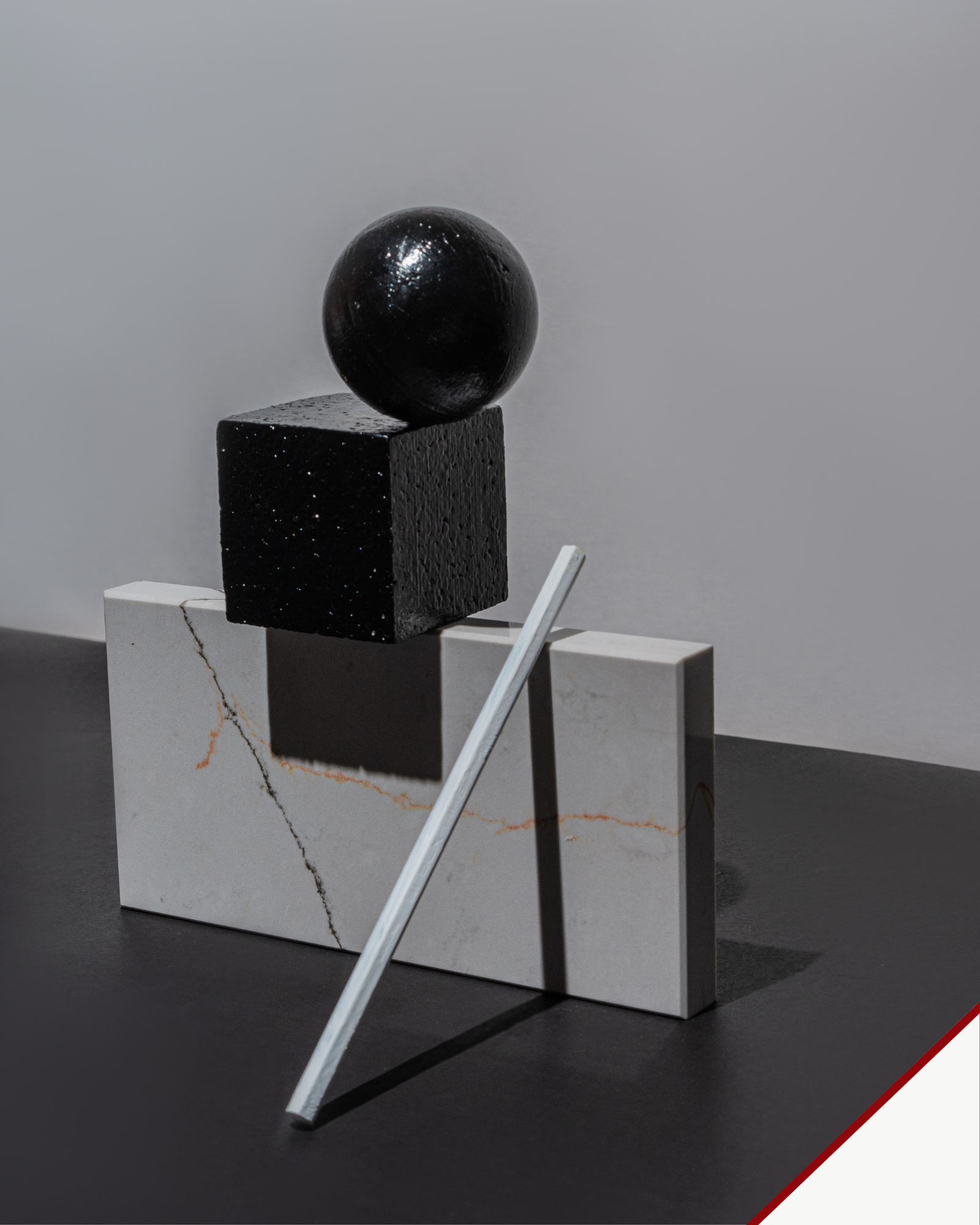 Explore Objects — sculptural still life with a black sphere and cube, pale stone blocks and a leaning metal rod.