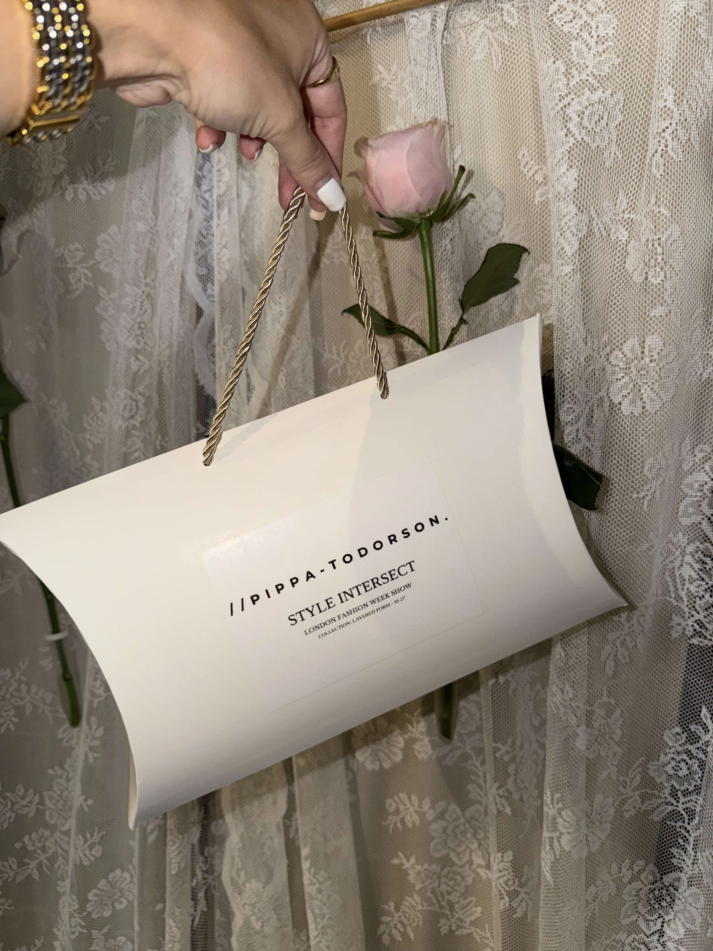 Pippa Todorson Style Intersect SS27 gift bag displayed against lace and pale pink flowers.