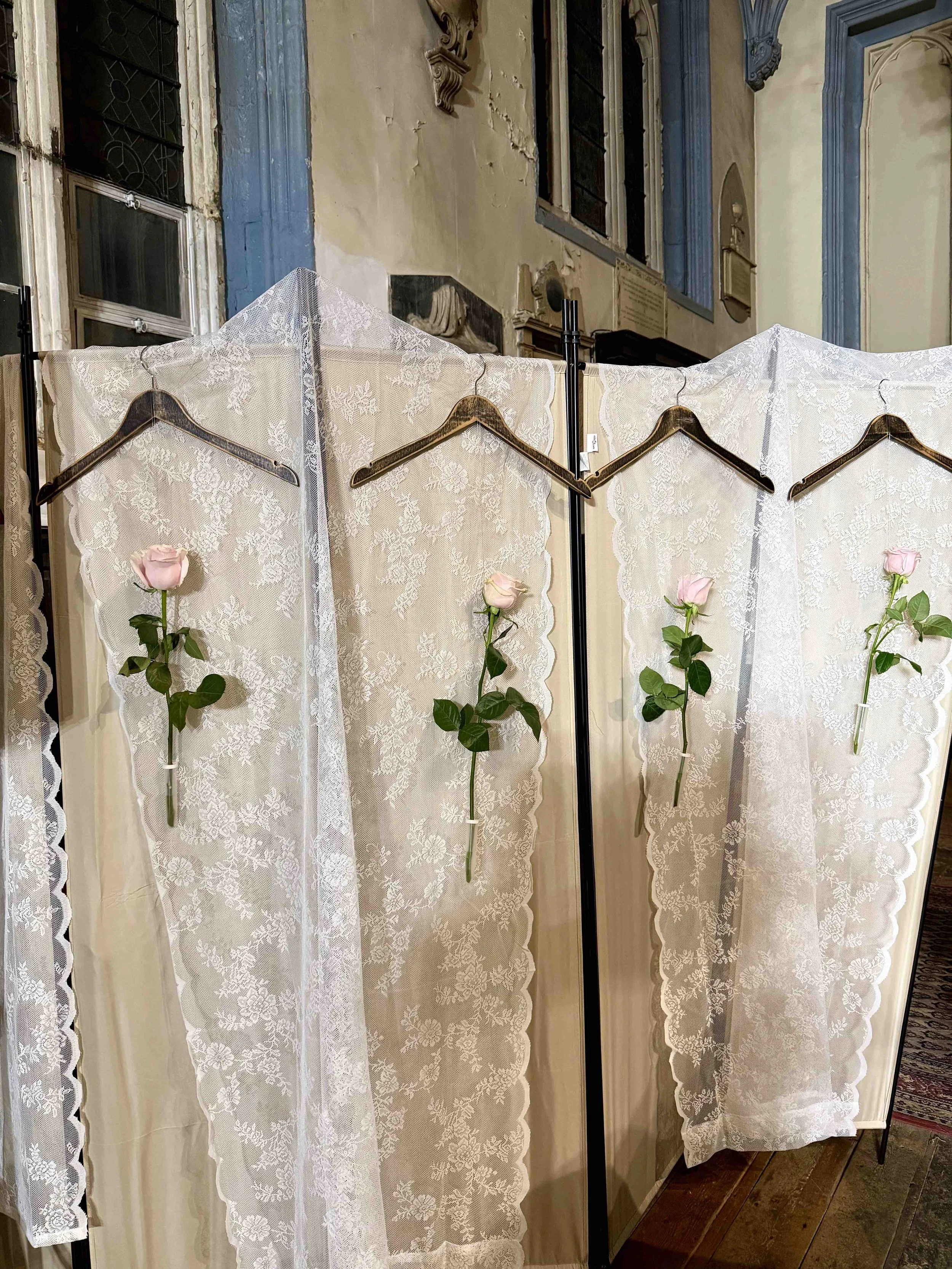 Lace panels, suspended clothes hangers and pale flowers inside the Style Intersect SS27 London Fashion Week venue.