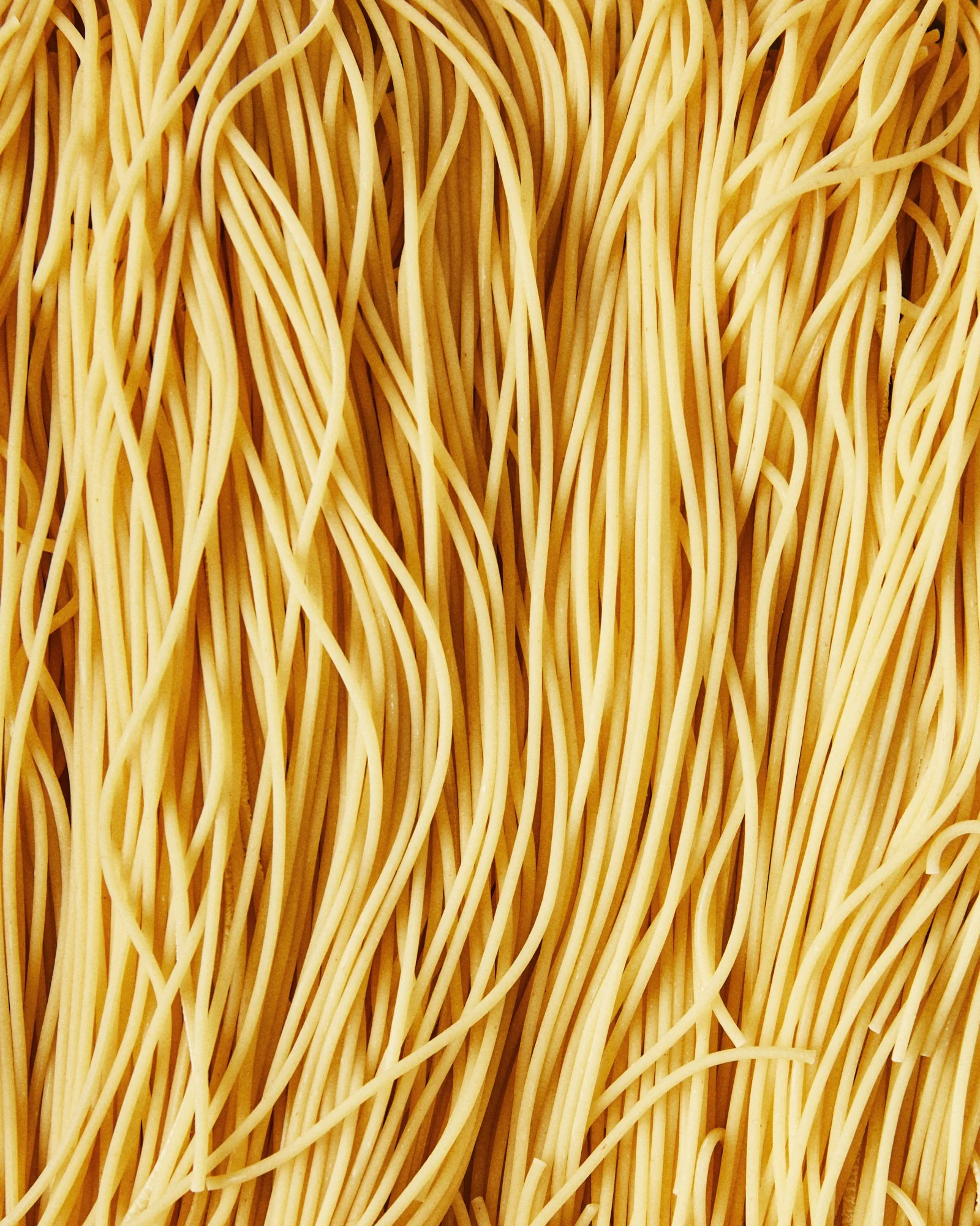 Close-up food photograph of long strands of fresh uncooked pasta.