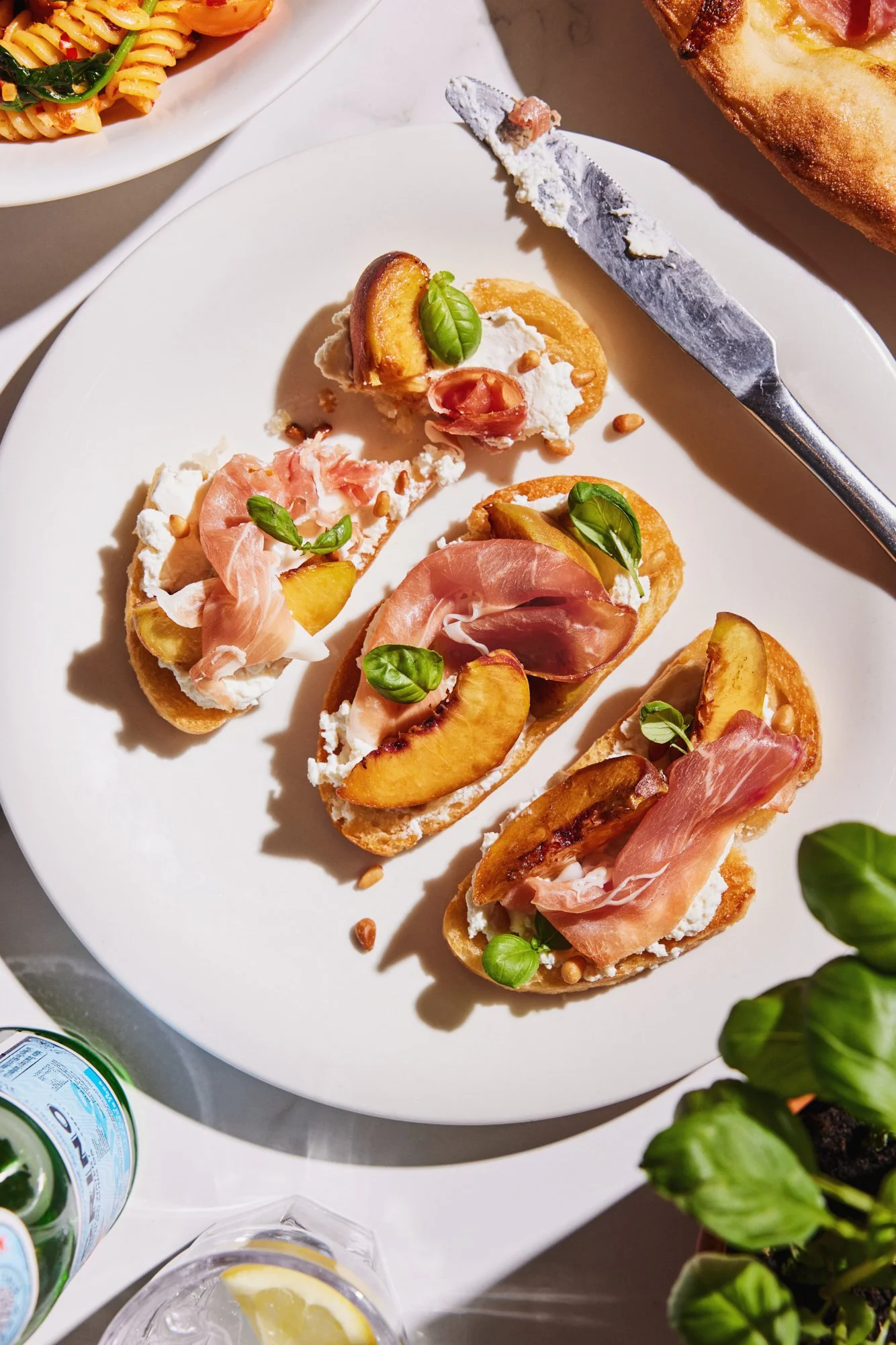 Overhead photograph of bruschetta topped with cured ham, peaches and fresh basil.