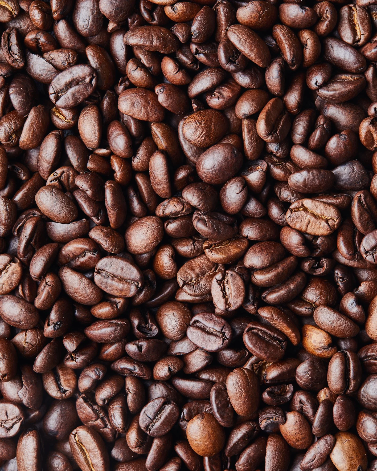 Close-up texture photograph of roasted coffee beans filling the frame.