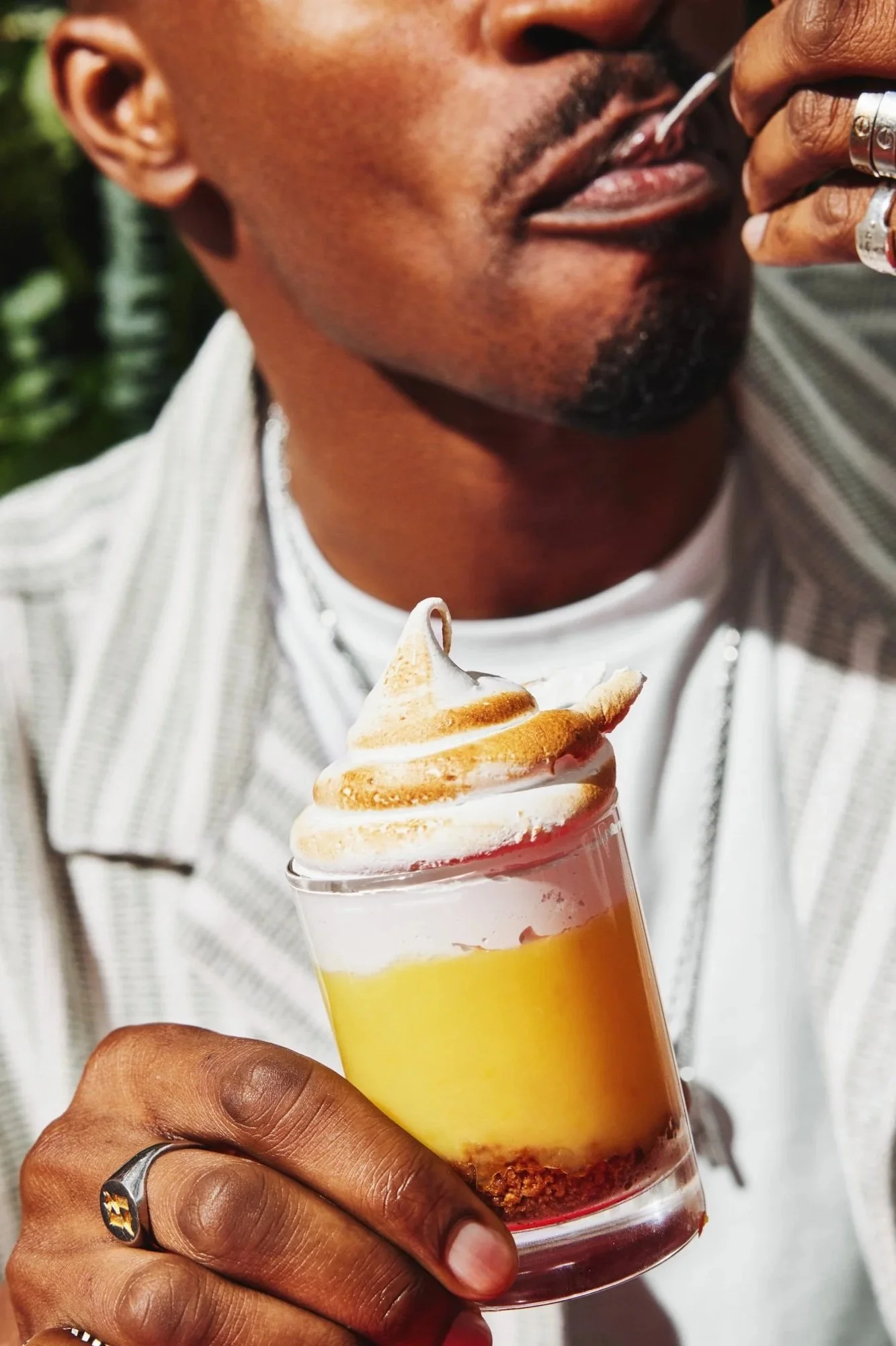 Man holding a layered yellow dessert topped with toasted meringue.