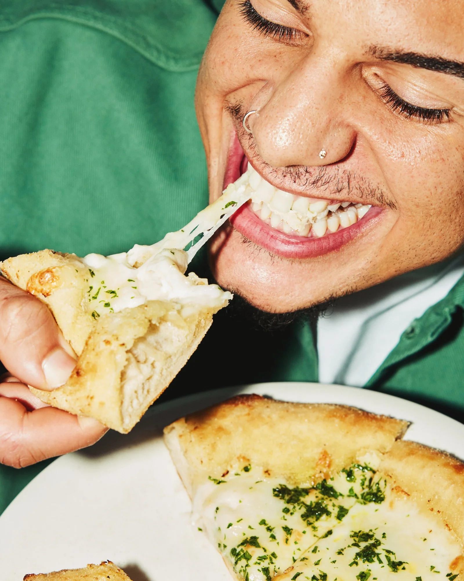 Smiling diner taking a bite of cheesy garlic bread.
