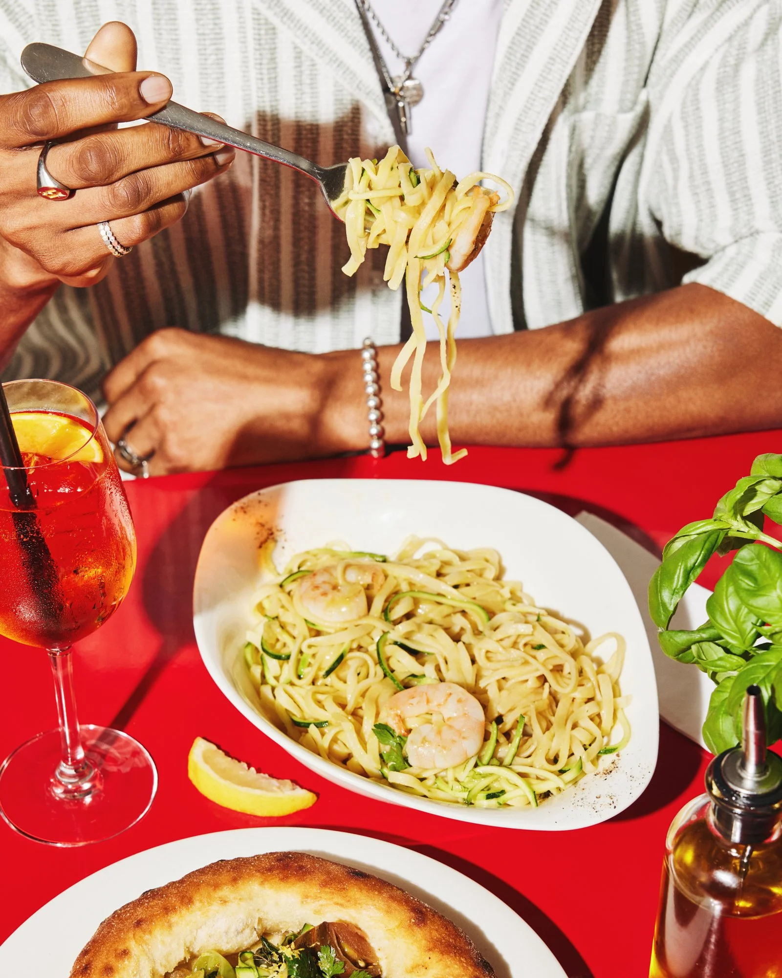 Diner lifting a forkful of pasta from a bowl of spaghetti at a red table.