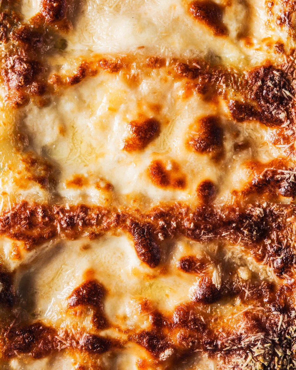 Extreme close-up of golden, bubbling cheese on freshly baked lasagne.