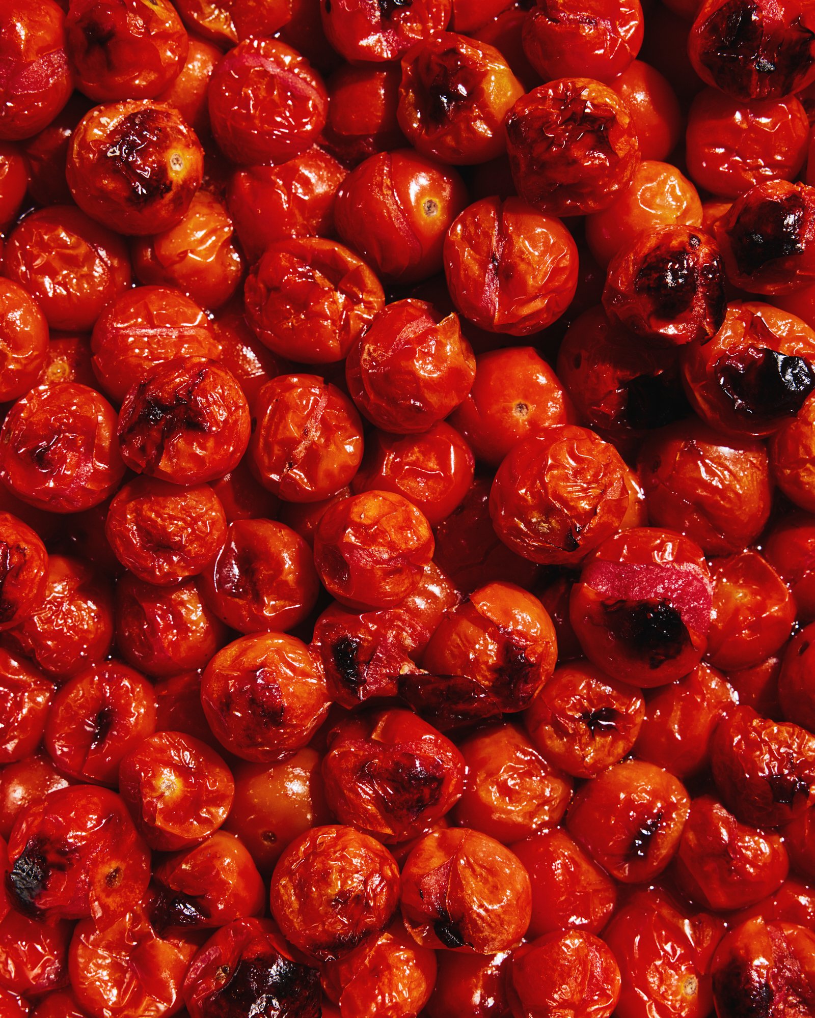Close-up food photography of glossy roasted cherry tomatoes.