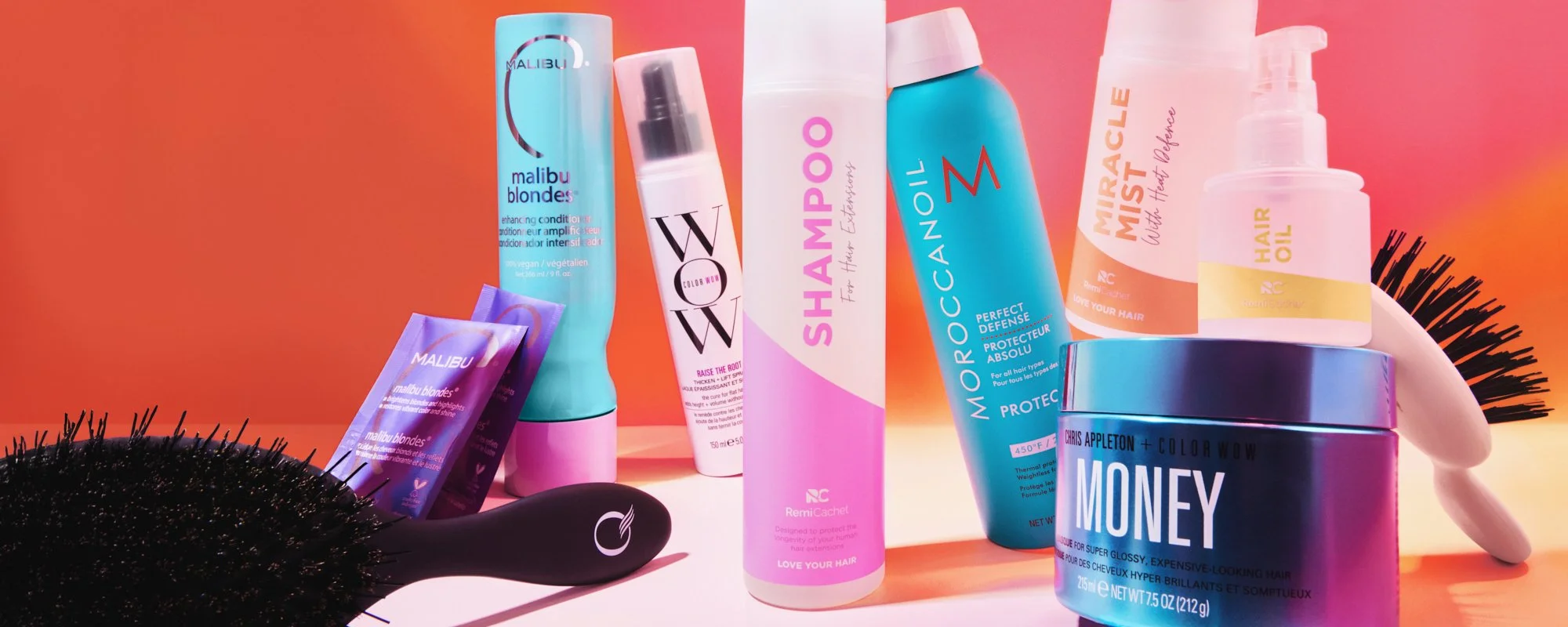 Colourful commercial product photography featuring haircare products from multiple beauty brands against a pink and orange background.