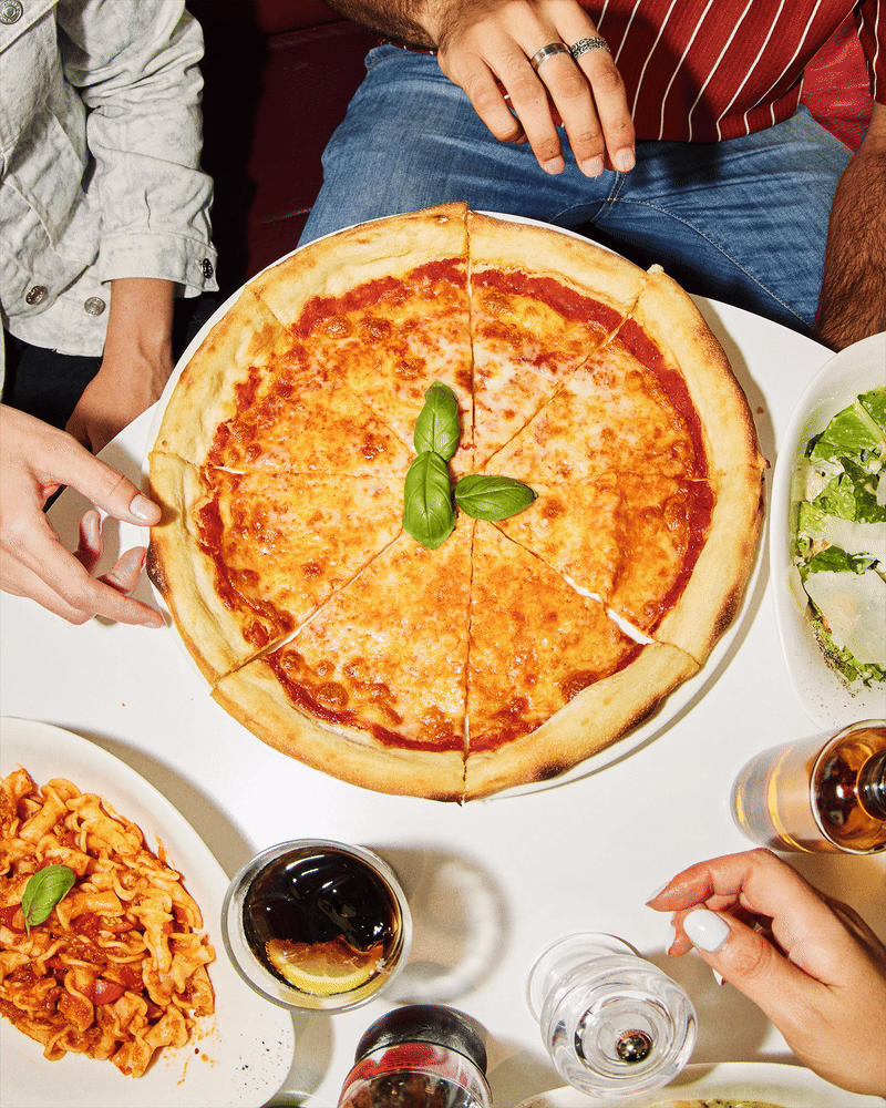 Stop motion GIF of a margherita pizza being shared at a restaurant table.