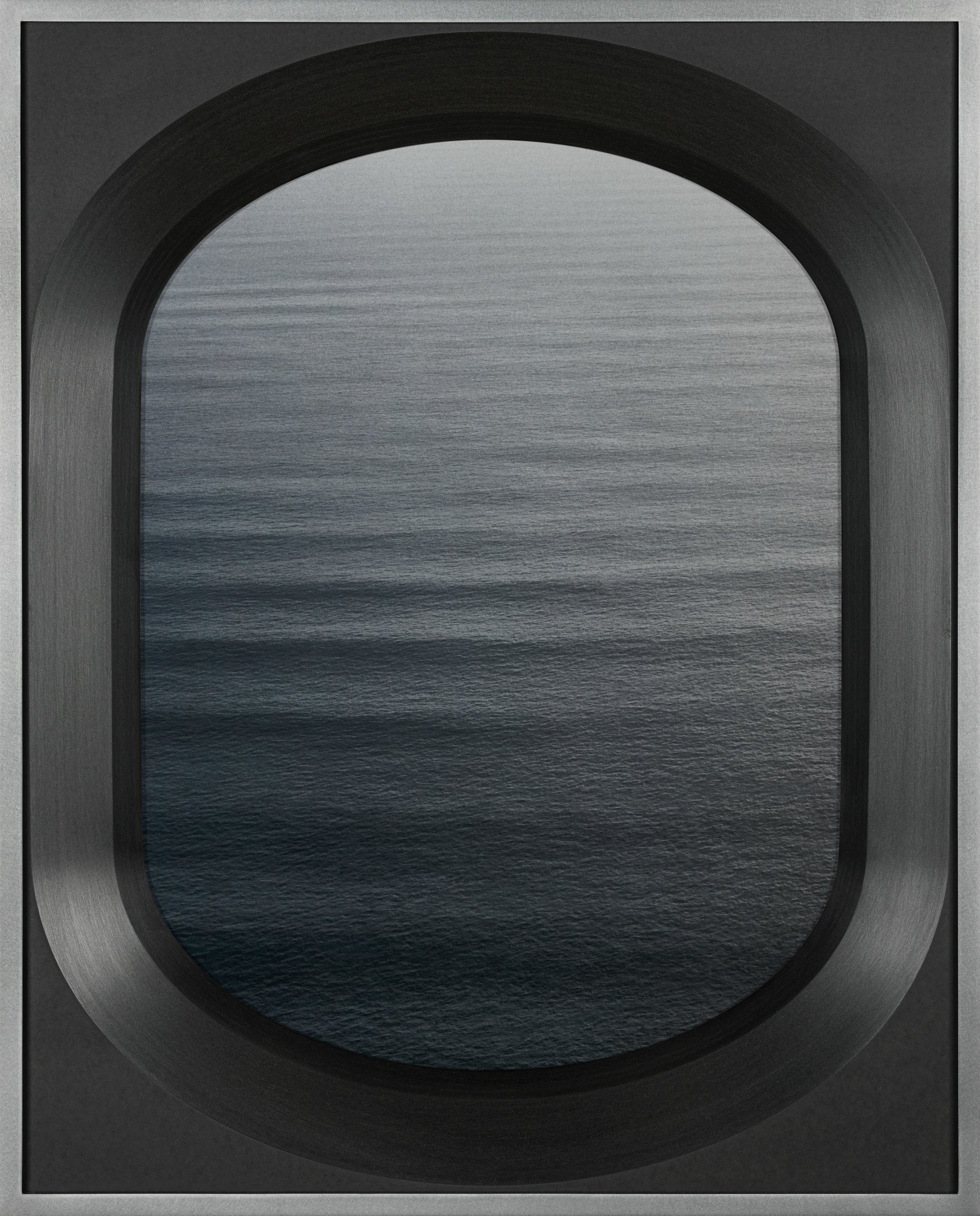 View of the ocean through a metallic or brushed metal arch-shaped window.