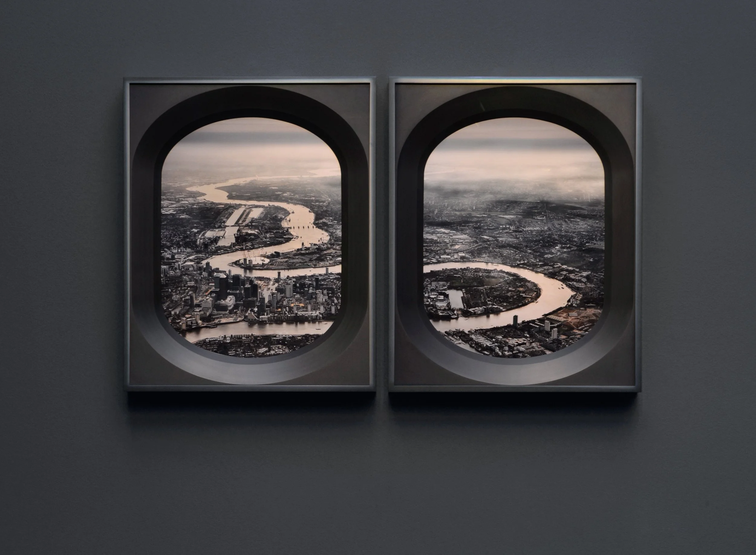 View of a city and river from an airplane window with two circular windows.
