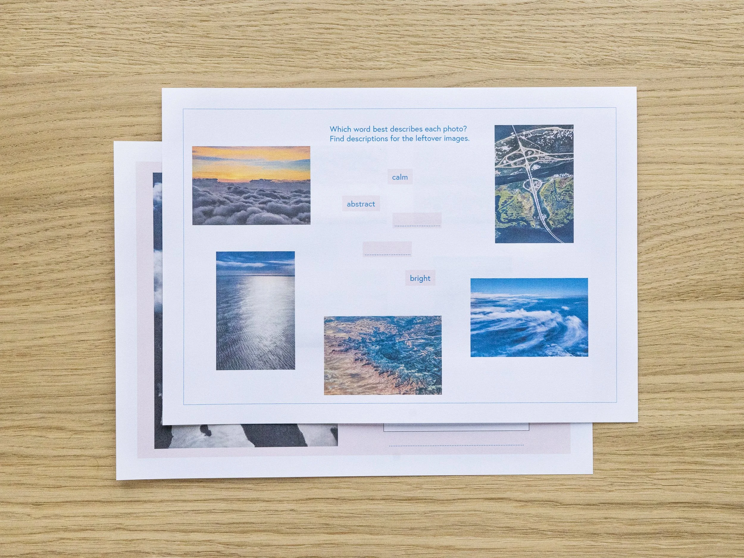Photograph of a printed sheet with multiple landscape photos and descriptive words on a wooden surface.