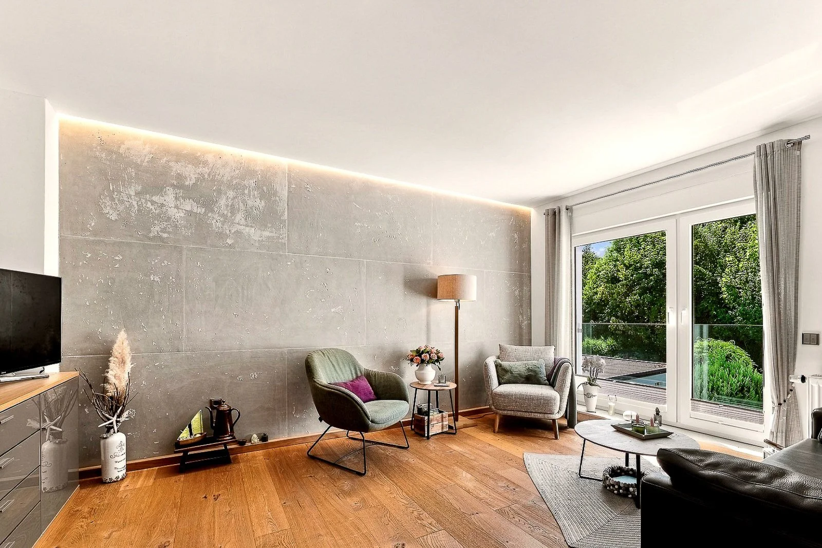 Modern eingerichtetes Wohnzimmer mit großem Fenster und Blick in den Garten.