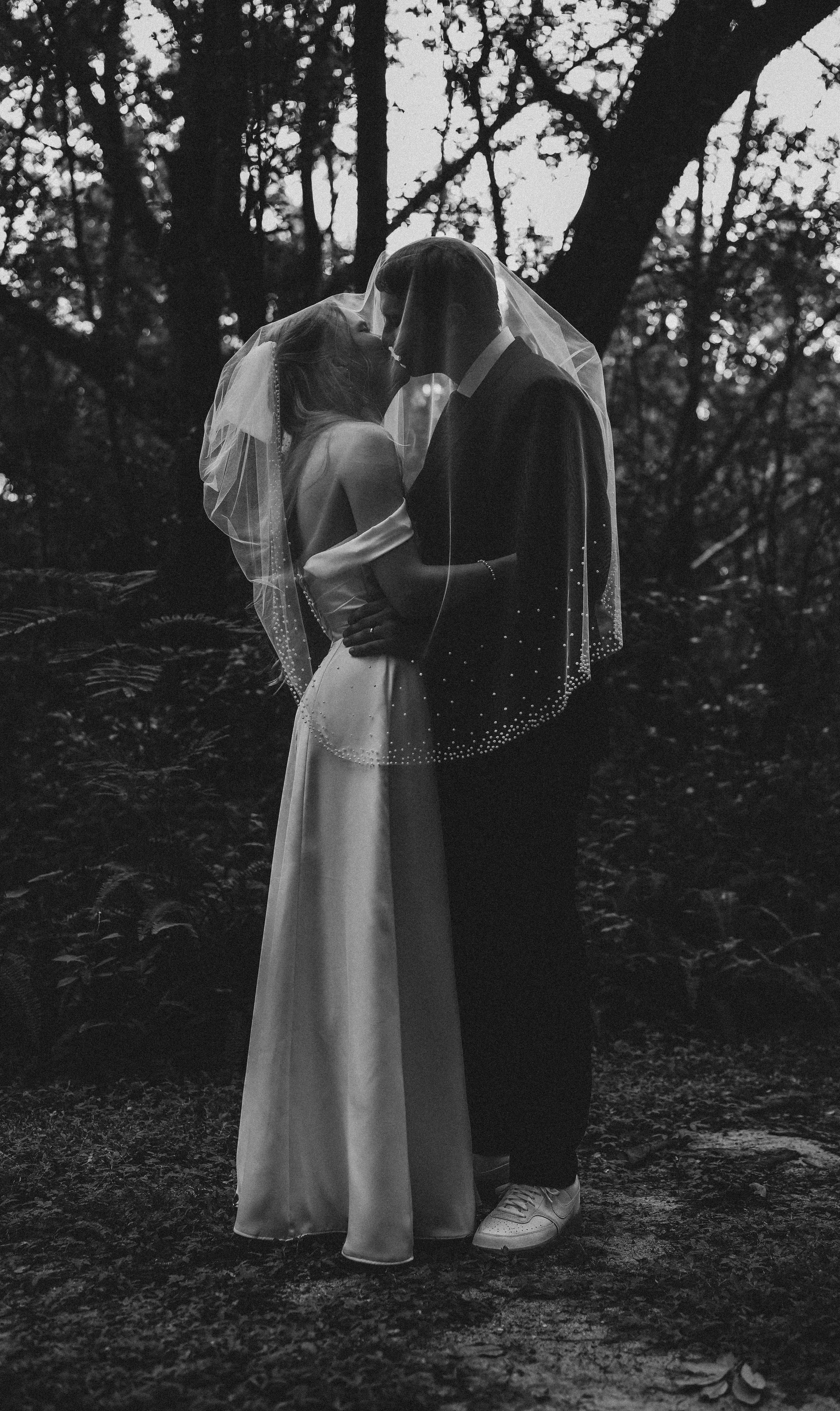 A bride and groom kissing beautifully on their wedding day in Florida. The Bride is in a stunning white wedding dress and the groom is in a black suit.