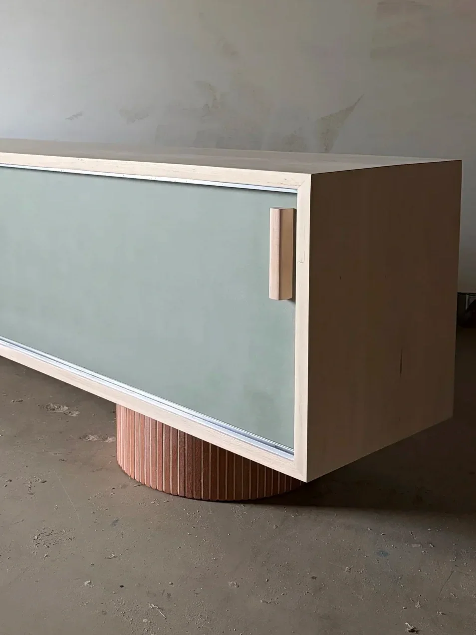 Modern wooden cabinet with a frosted glass door and a rounded wooden base.