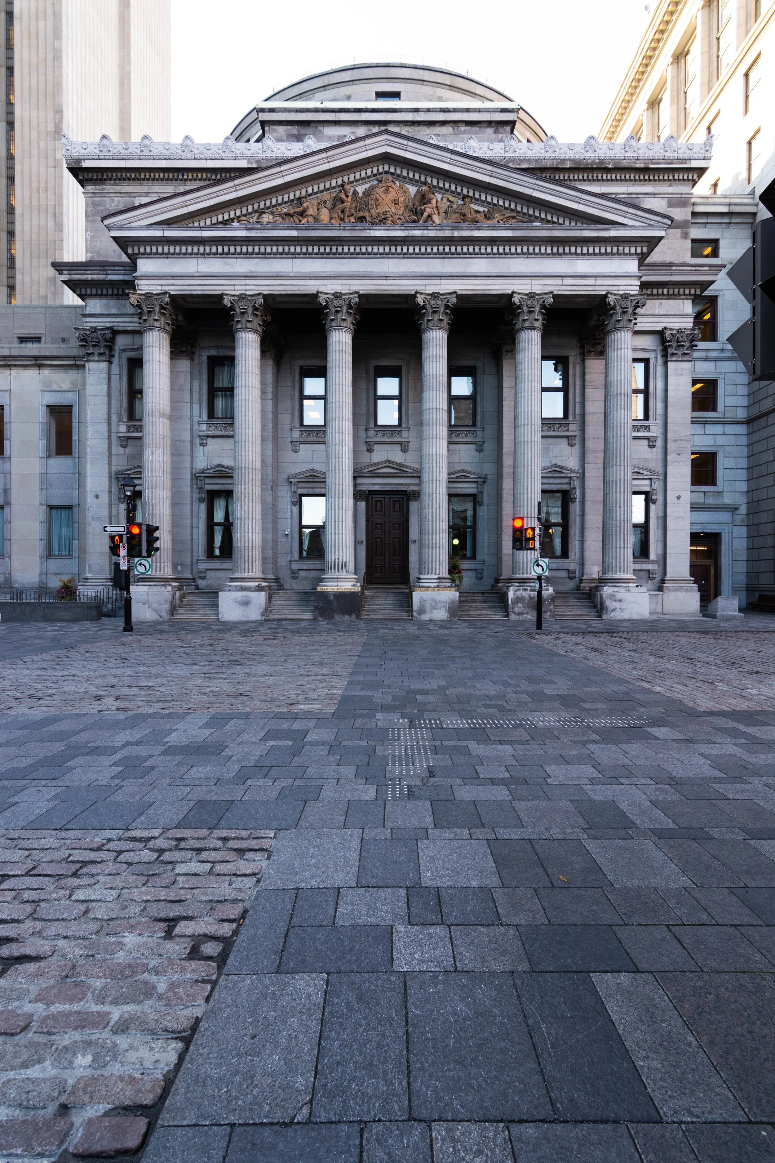 Front view of a historic government building with classical columns, architectural sculptures, and traffic lights at the entrance.