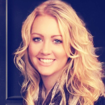 Portrait of a young woman with blonde, curly hair smiling at the camera.
