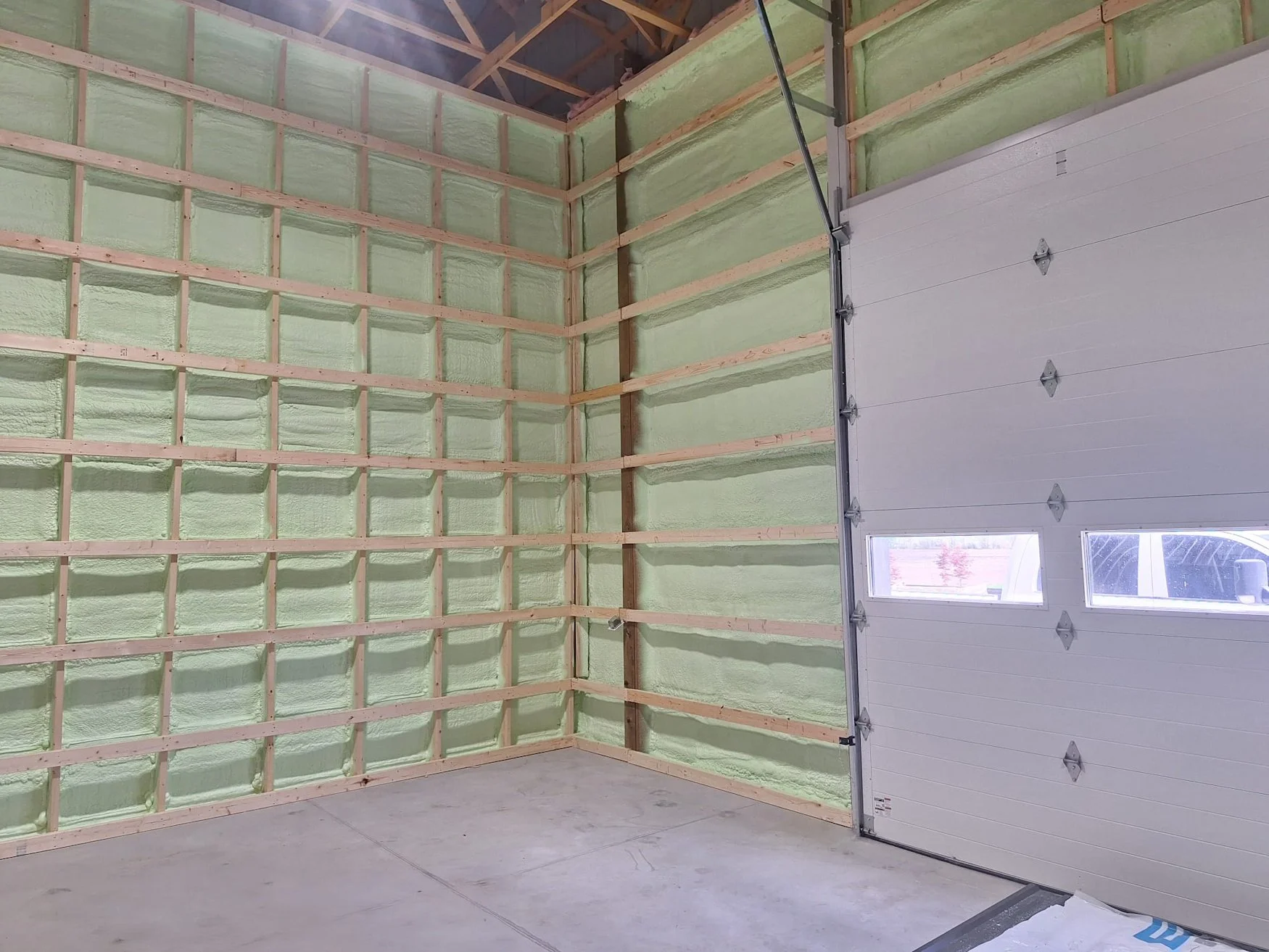 Construction site with a partially built multi-story building wrapped in Tyvek HomeWrap, scaffolding, and a white pickup truck parked in front.