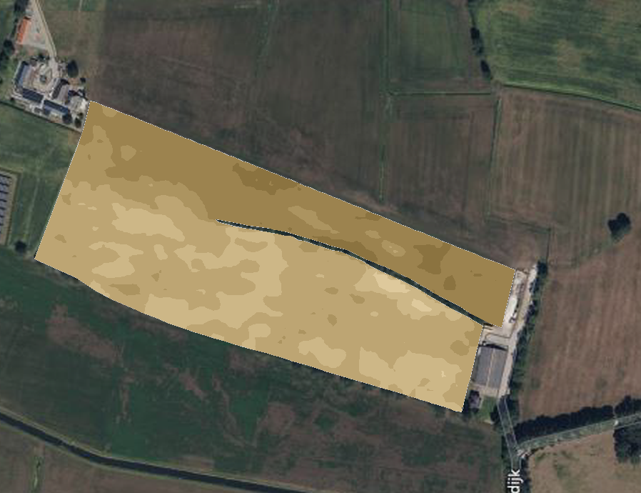 Lichtbruine Abraham van Rijnstraat over een groen landschap, met schuren en een pad.