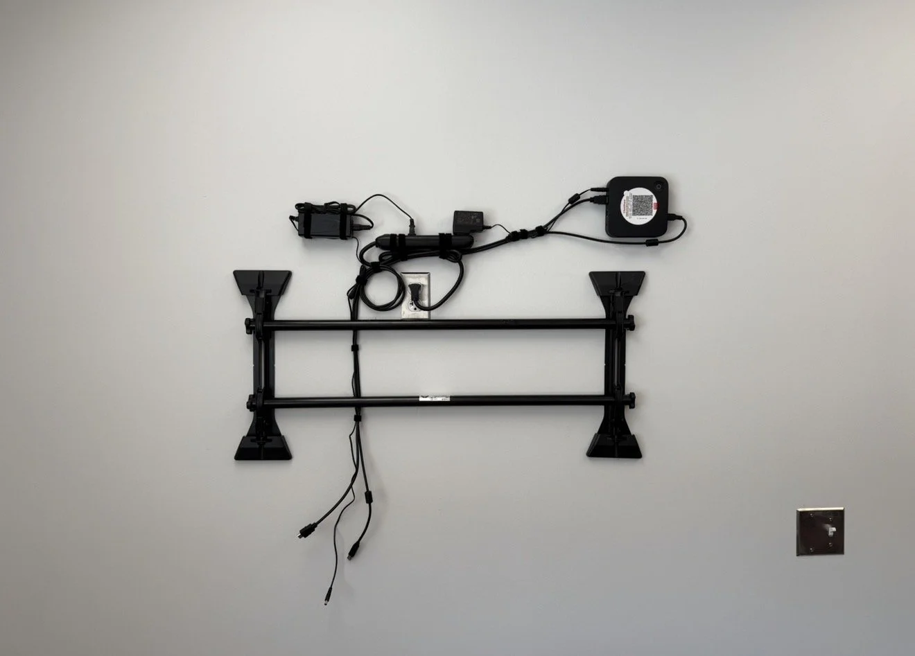 Wall-mounted cable management system with electrical components and cords.