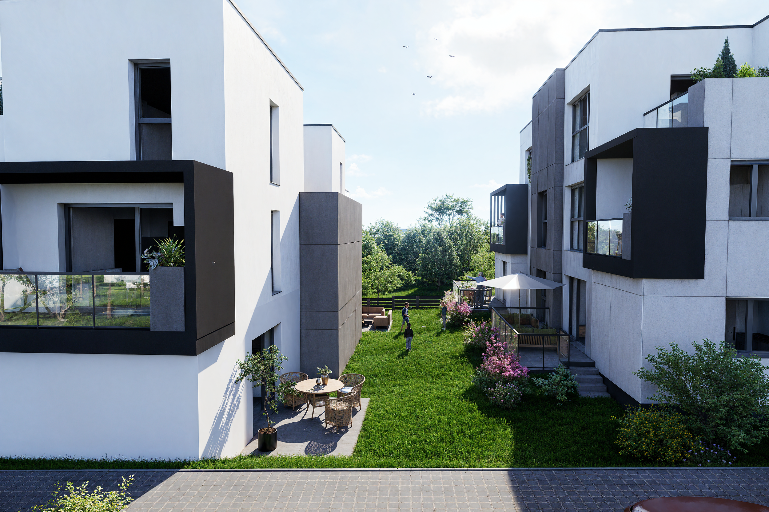 Modern white apartment buildings with black accents, green lawn, outdoor seating, and people enjoying the backyard garden area.