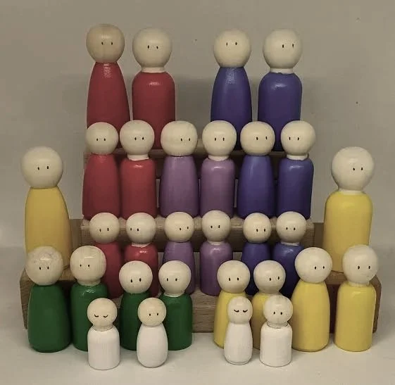 Figuras de madera en forma de personas de diferentes colores y tamaños, dispuestas en filas sobre una base de madera.