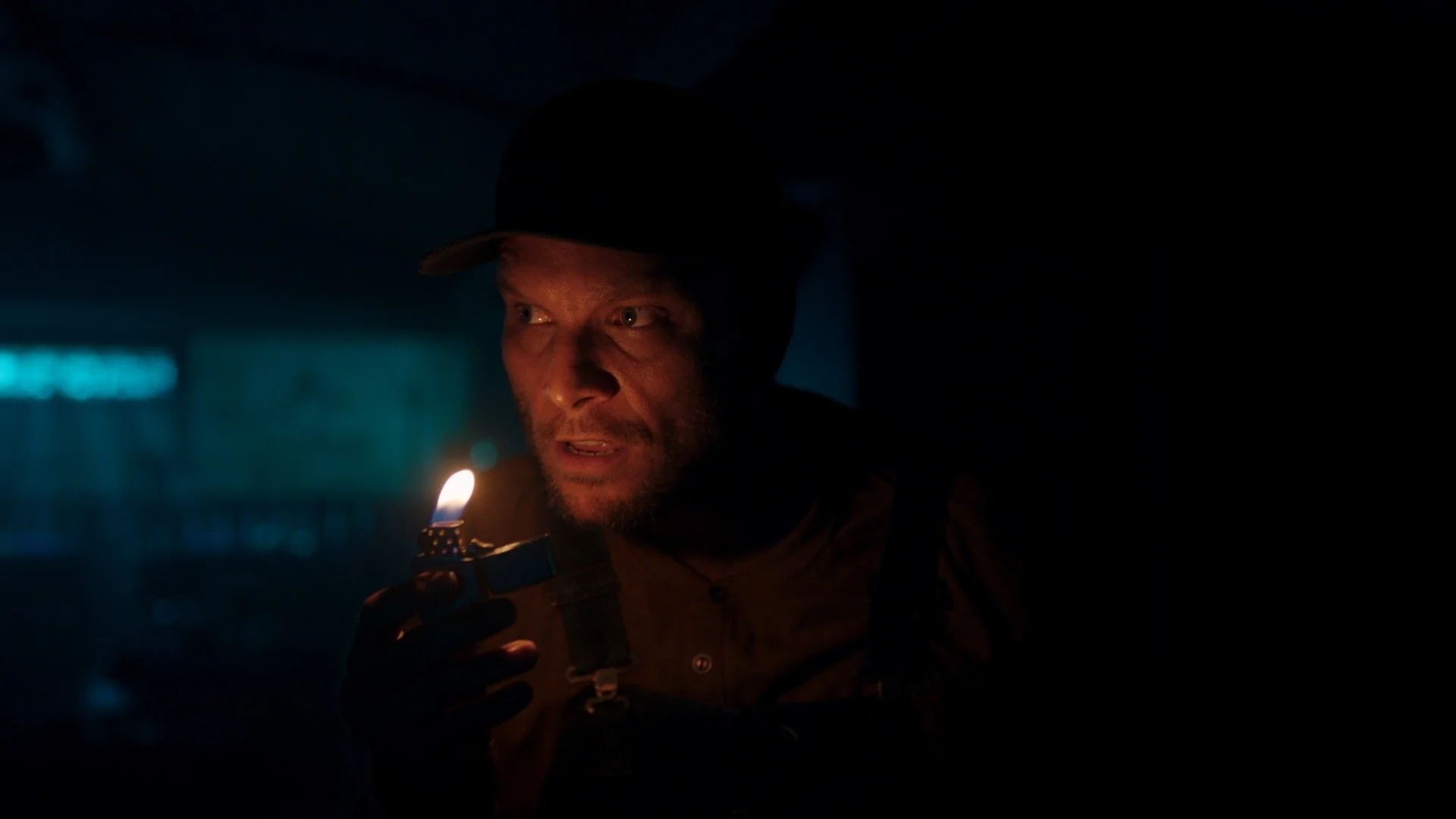Cinematic still photographed by Director of Photography Shamus Whiting-Hewlett, featuring a man holding a lighter close to his face in a dark setting.