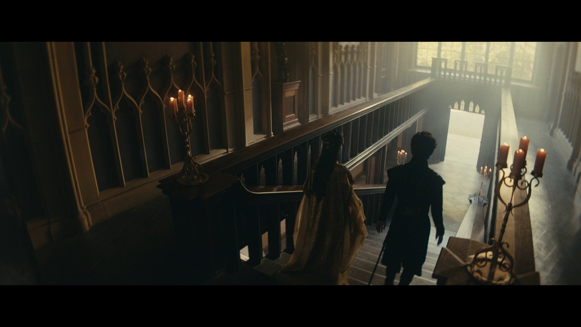 Cinematography by Shamus Whiting-Hewlett, featuring two people descending an ornate wooden staircase in a dimly lit historic interior.