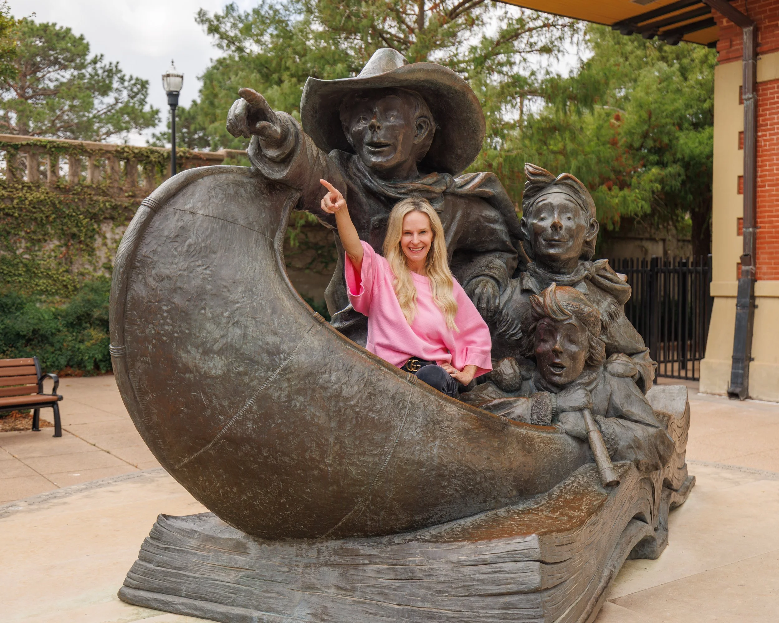 Tonya Harbin, a woman in a pink sweater, poses with a bronze sculpture of a scene from William Joyce's book Santa Calls.