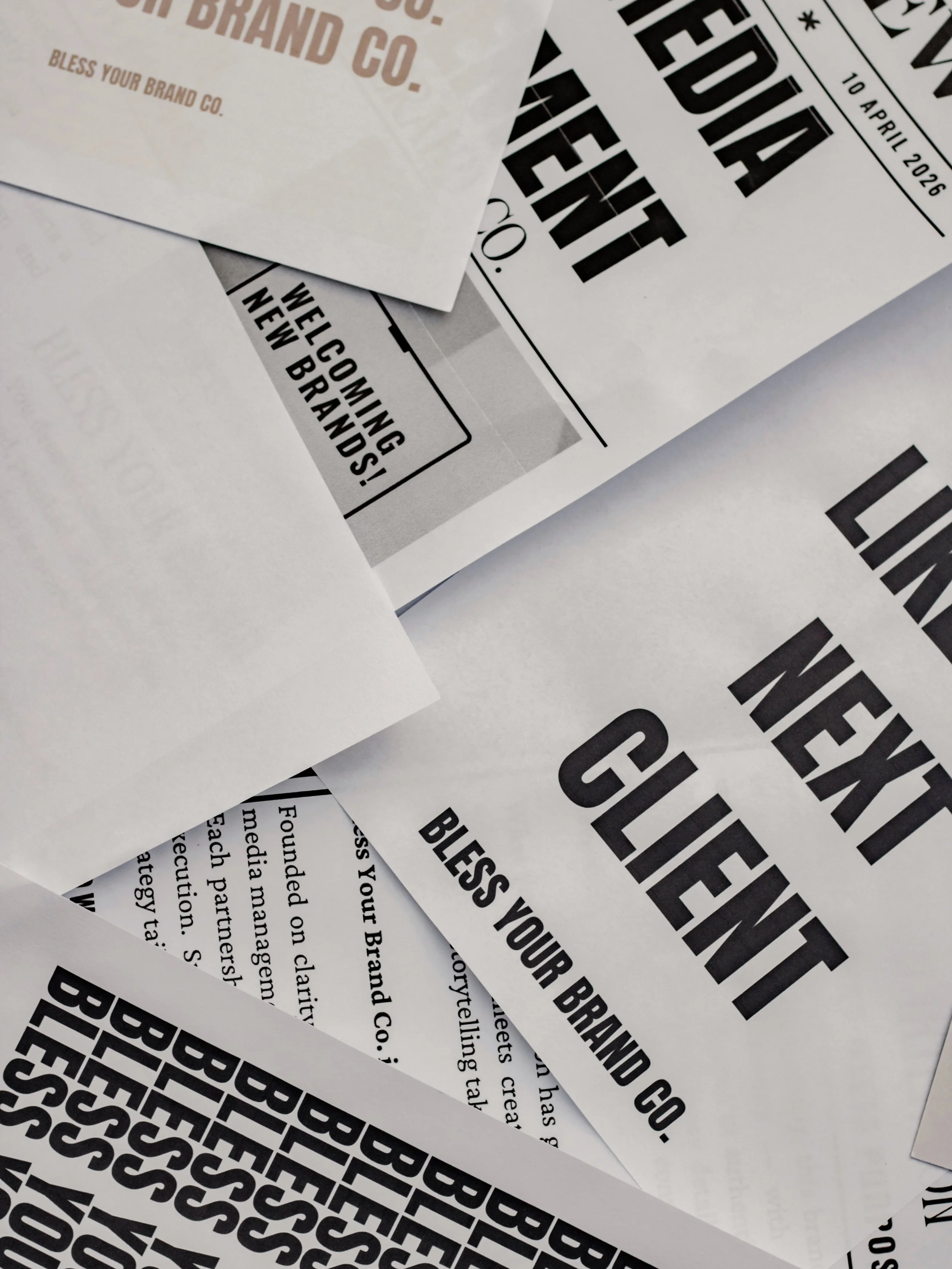Close-up of several sheets of paper with bold text, including dates and greetings for a brand or company event.