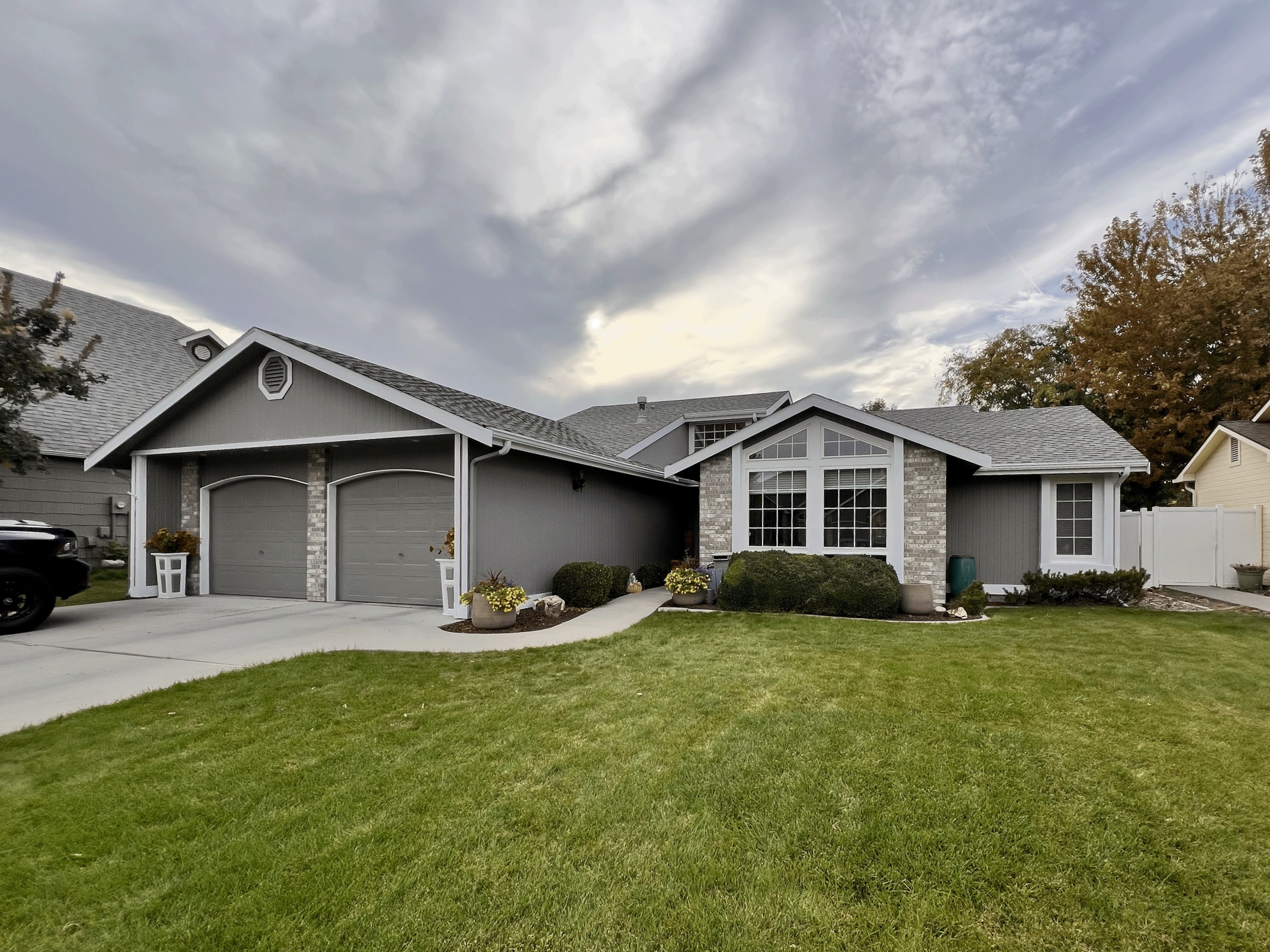 A freshly painted grey exterior on a single level home with two garages on a cloudy day