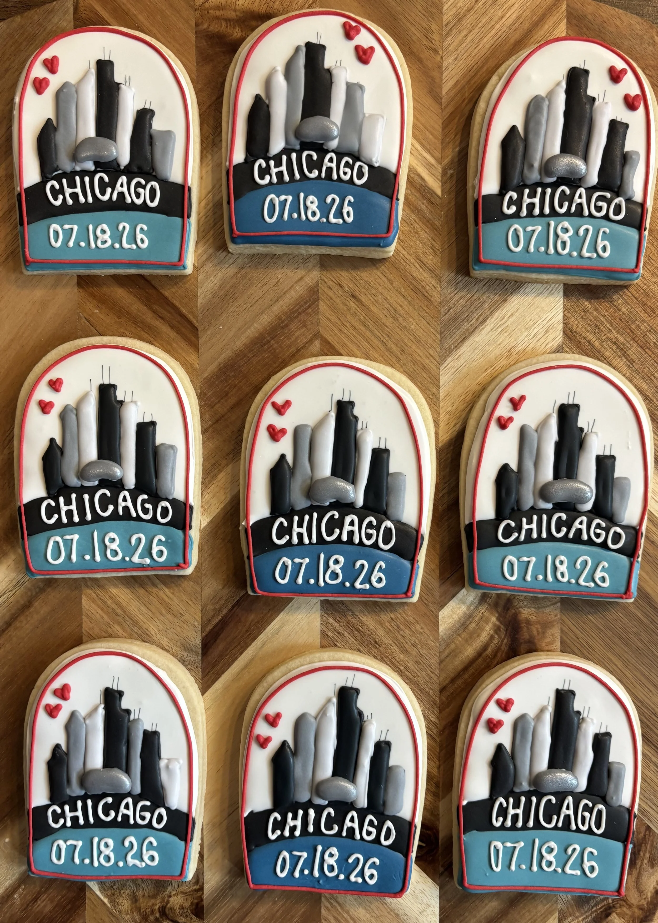 Decorative cookies with Chicago skyline, the word 'CHICAGO', date '07.18.26', small red hearts, and a red border, on a wooden surface.
