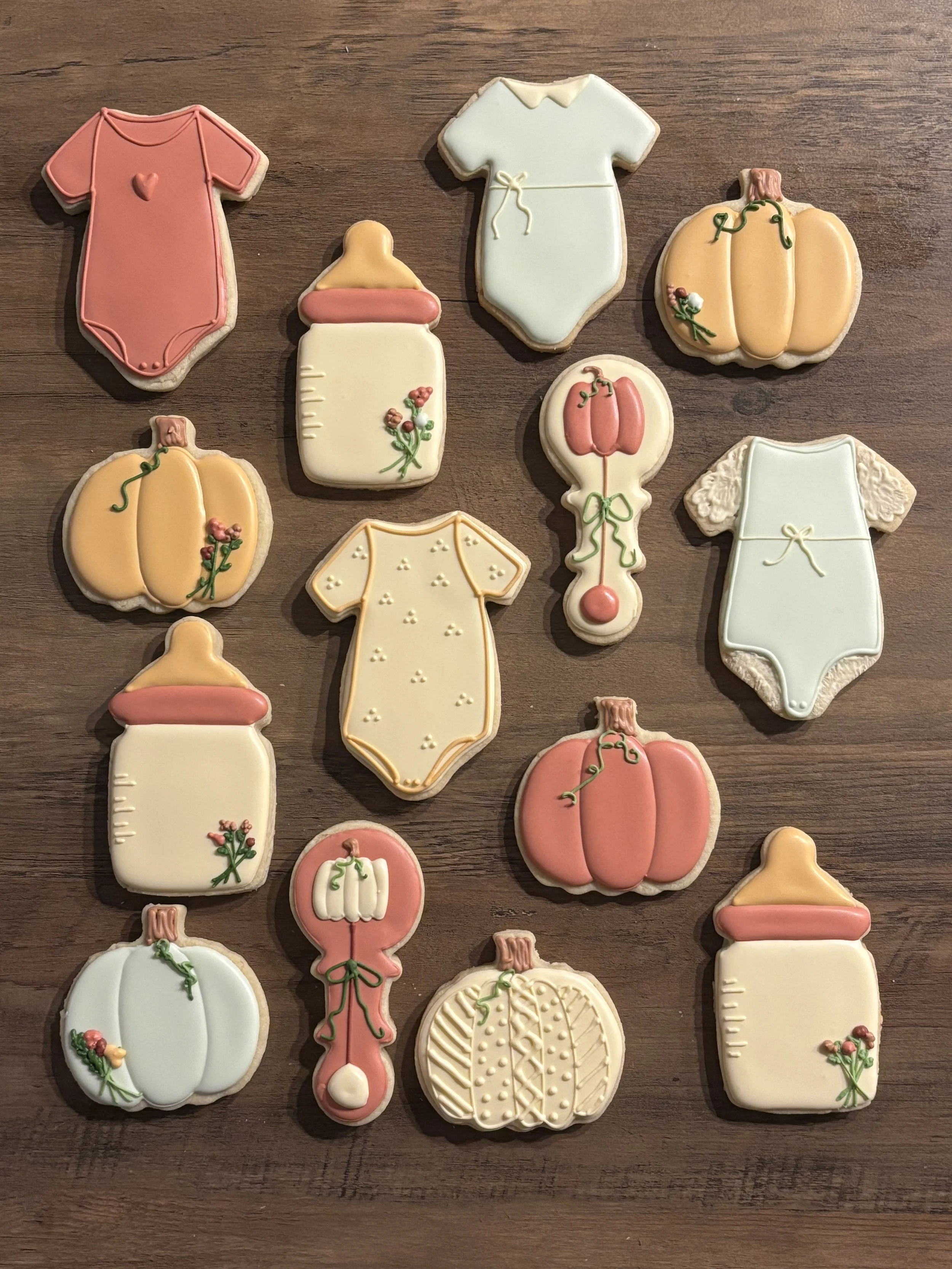 Collection of decorated cookie with autumn and pumpkin themes on a wooden surface.
