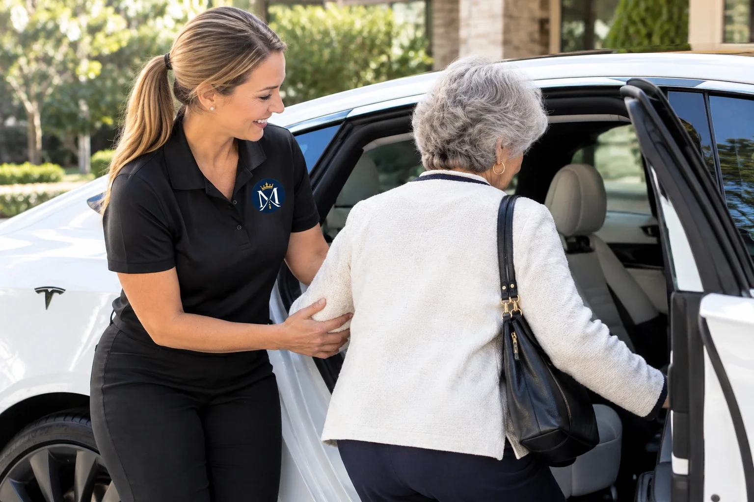 Monarch Elite Transport caregiver helping an older woman into a white vehicle