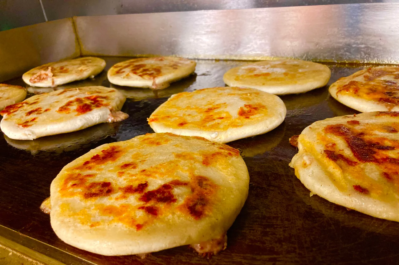 Several pieces of flatbread with cheese and sauce cooking on a griddle.