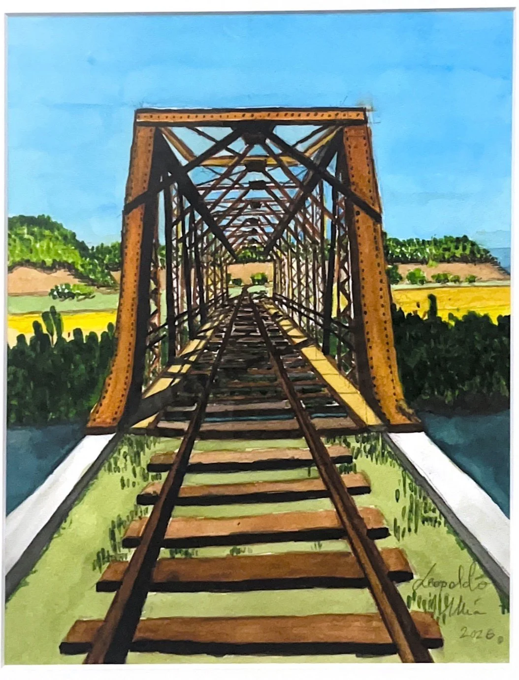 Puente de fer con vías de tren sobre un río, con paisaje de campo y colinas verdes y amarillo en el fondo, bajo un cielo azul